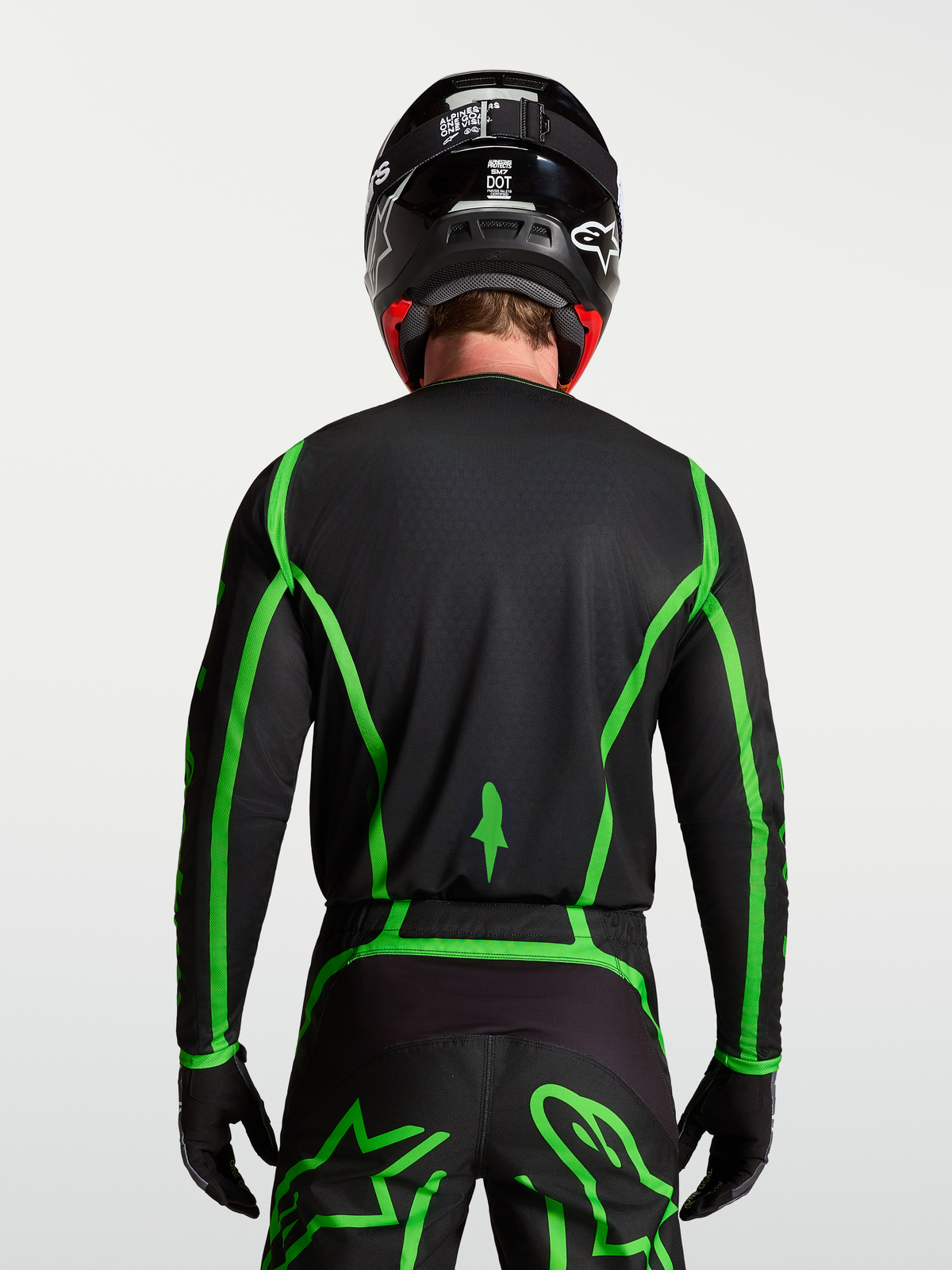 Alpinestars Fluid Apex V2 tröja för motocross, svart och neongrön, bakifrån på modell som visar förlängt ryggslut.