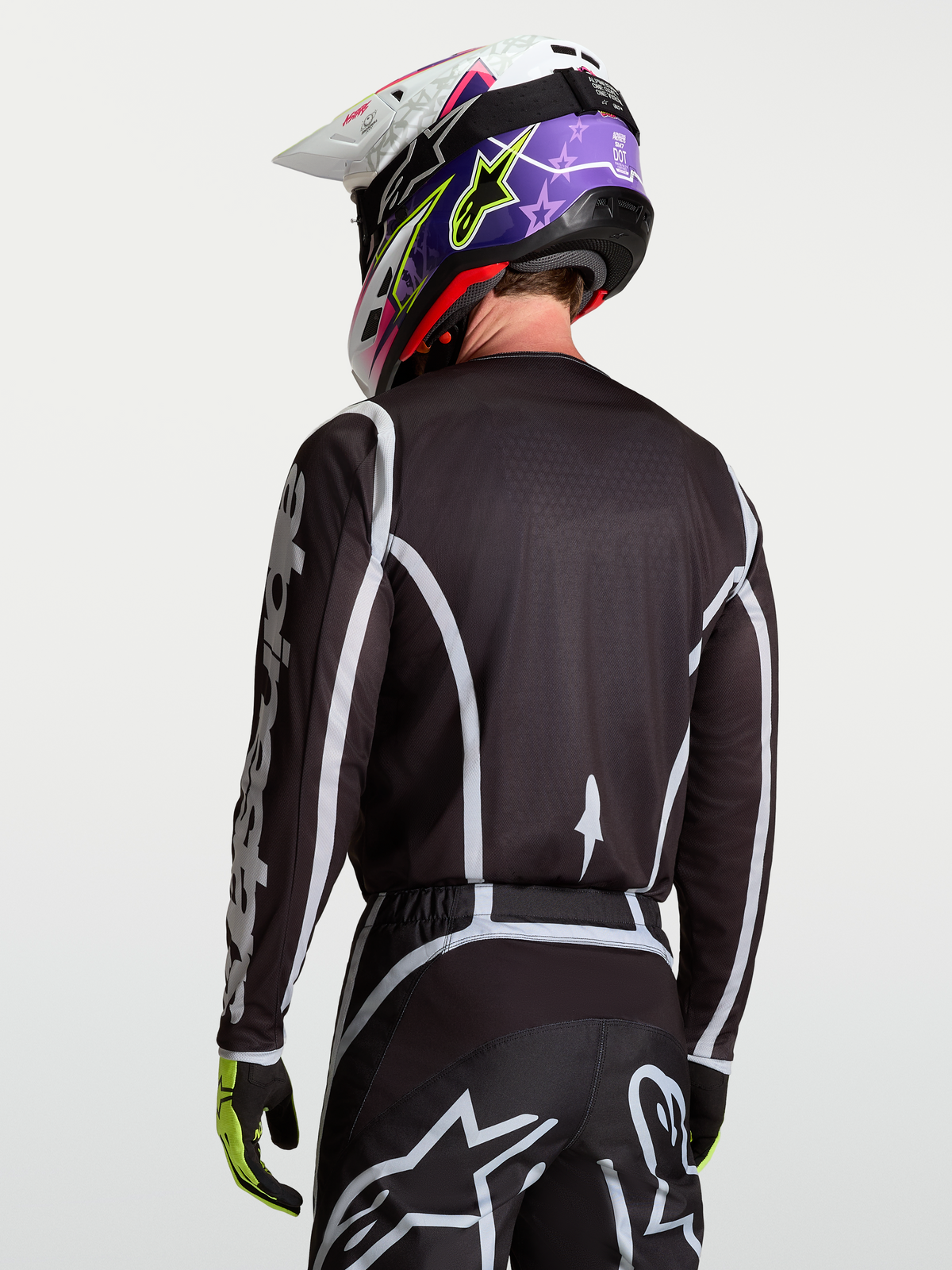 Alpinestars Fluid Apex V2 tröja, motocrosströja i svart och silver, modell sedd bakifrån, fukttransporterande polytyg och ergonomisk skärning för racing.