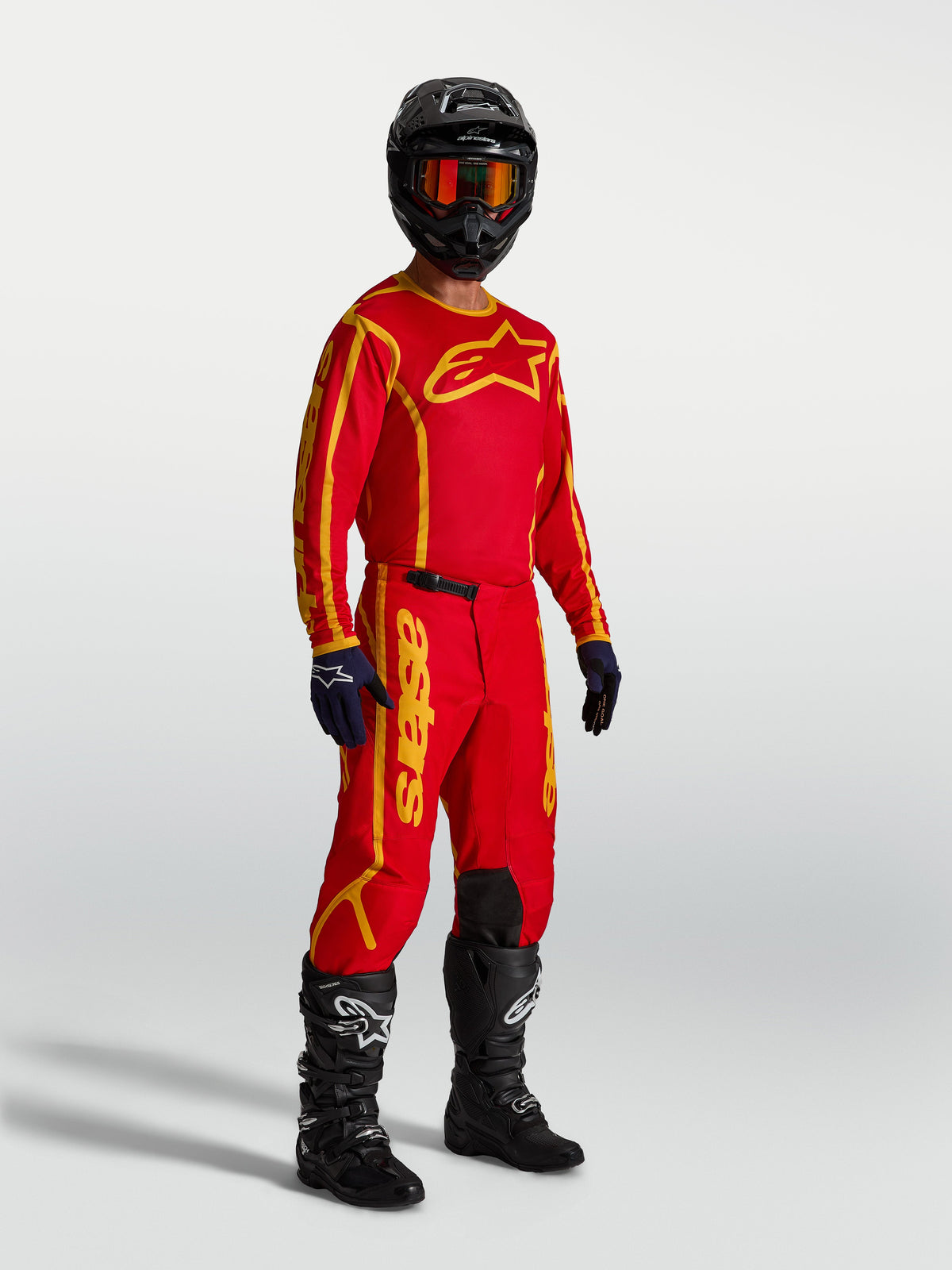 Alpinestars Fluid Apex V2 tröja, motocrosströja för herr, röd och guld, andningsbart fuktavledande polytyg, atletisk passform för terrängkörning, på modell med full utrustning.