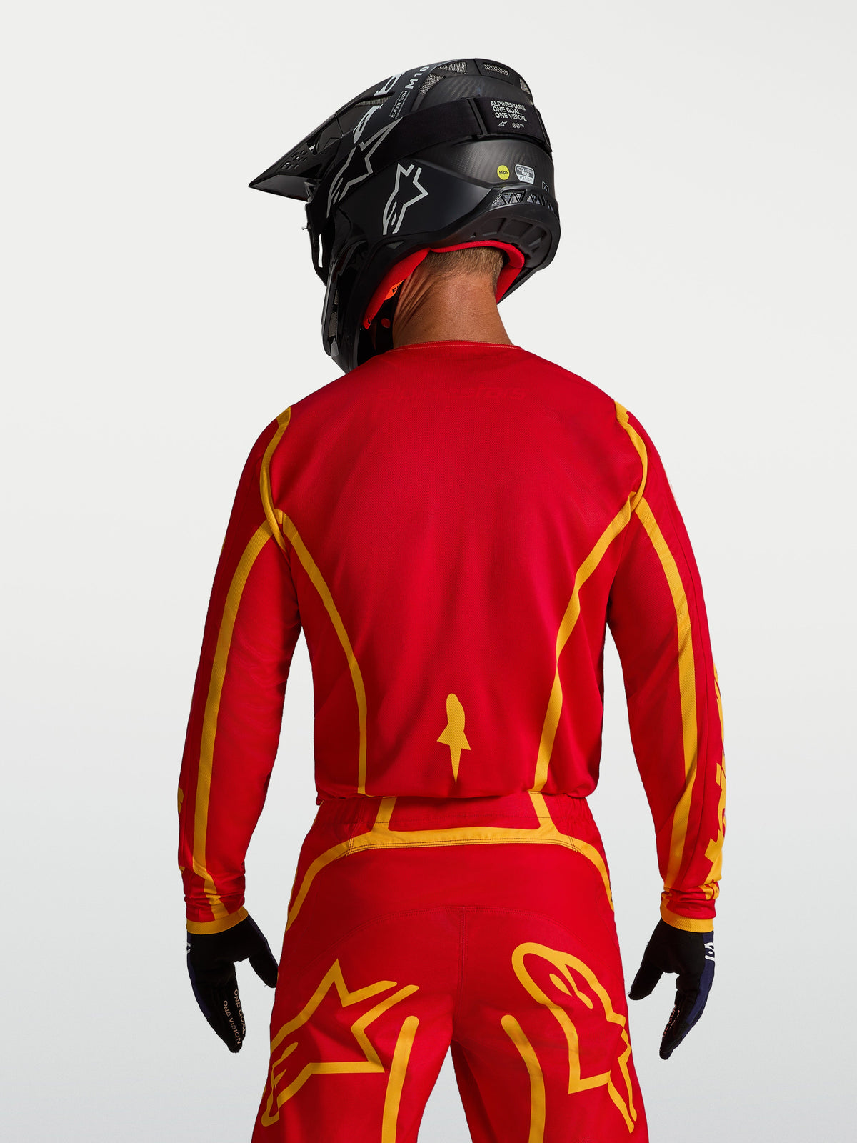 Alpinestars Fluid Apex V2 tröja, motocrosströja för herr, vy bakifrån i rött och guld, ergonomisk skärning med andningsbart tyg, optimerad för terrängkörning.