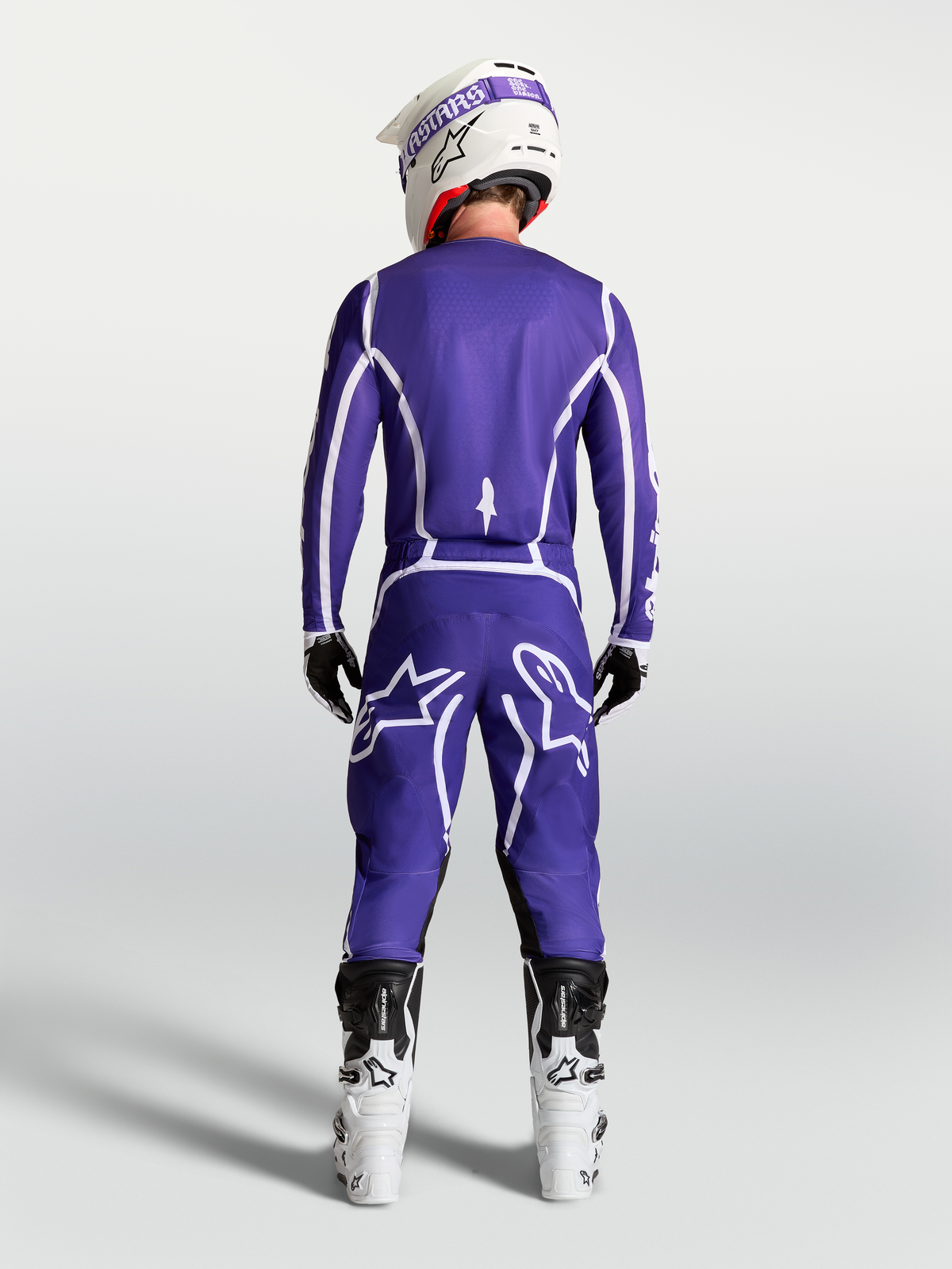 Alpinestars Fluid Apex V2 tröja, mörkblå och vit motocrosströja, vy bakifrån på förare med matchande byxor och vita motorcykelstövlar