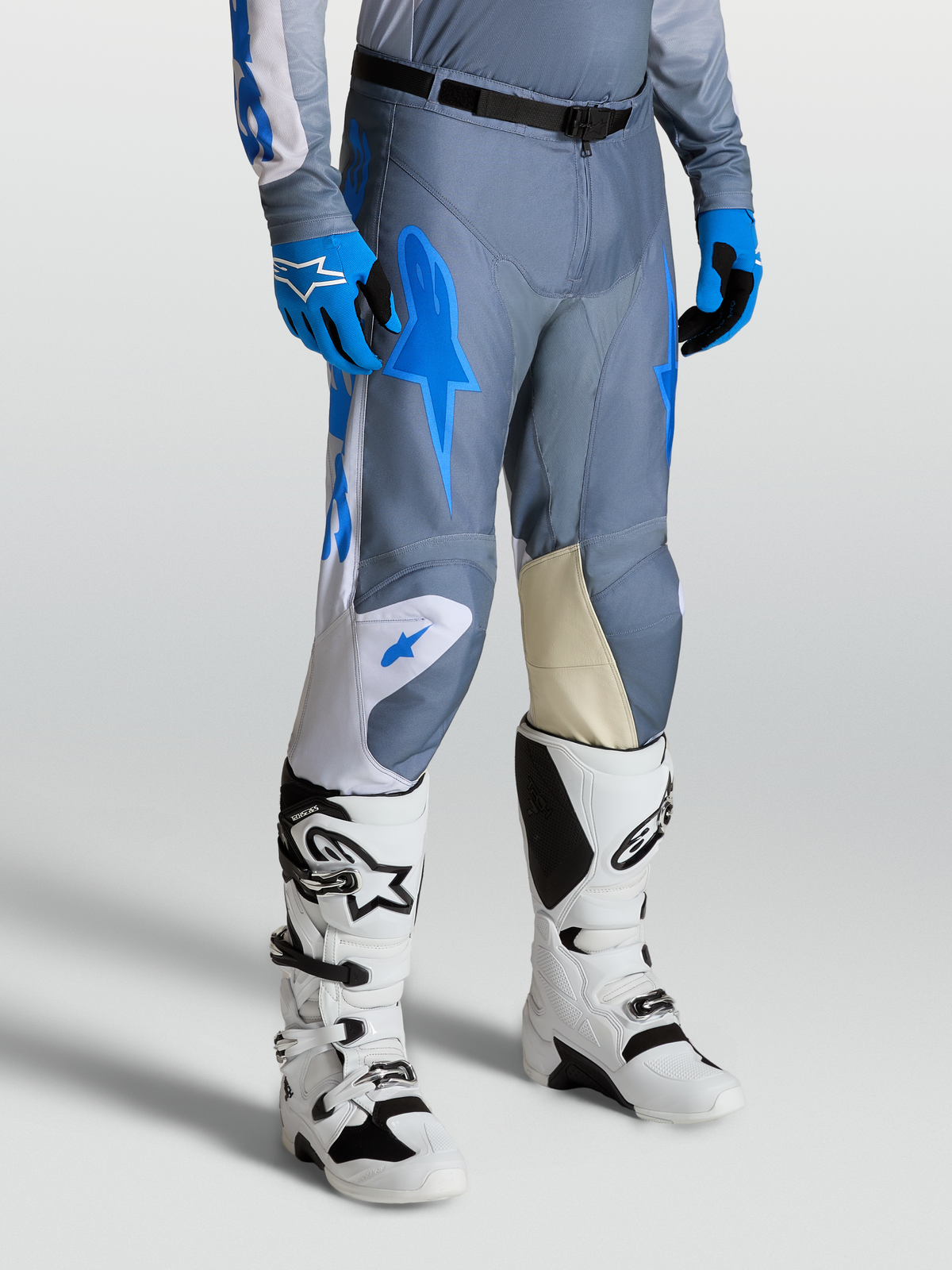 Alpinestars Racer Amber byxor, motocrossbyxor för herr i grått och UCLA-blått med knäpaneler i getläder och vita Techstar-stövlar.