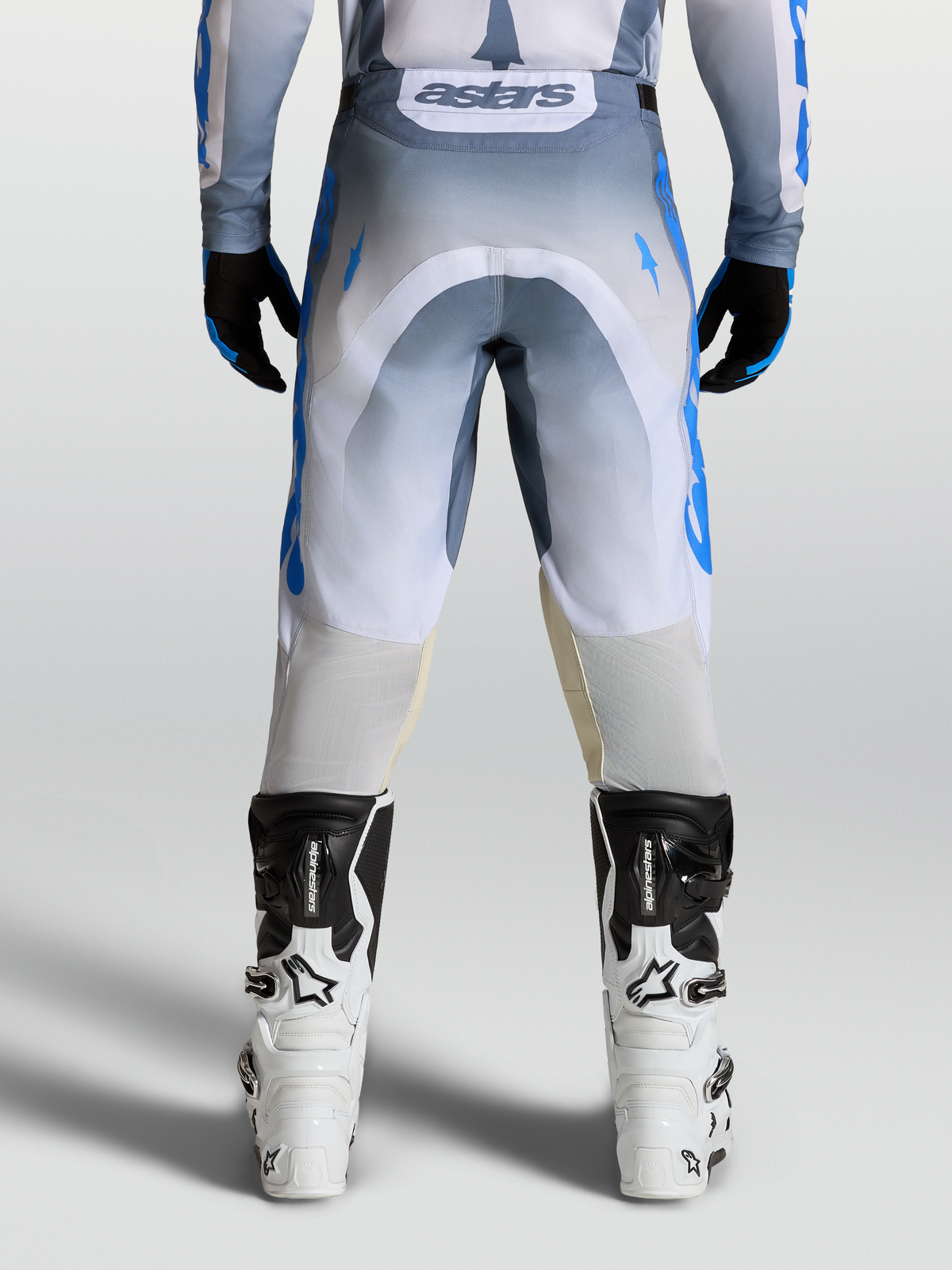 Alpinestars Racer Amber byxor, herrmotocrossbyxor, grå och blå, bakifrån på modell med vita stövlar, hållbart 600D polytyg