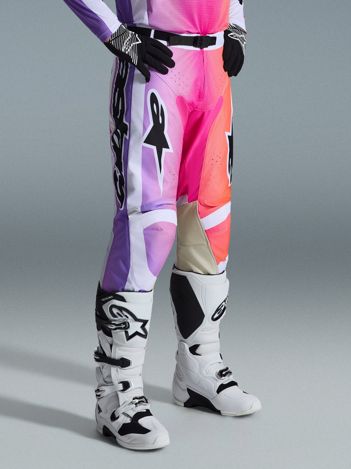 Alpinestars 2026 Racer Air Portl byxor, motocrossbyxor, flerfärgad grafik med lila, rosa och orange färgtoningar, bärs med vita och svarta motocross-stövlar och svarta handskar, med tävlingspassform och beige läderpaneler på insidan av knäna
