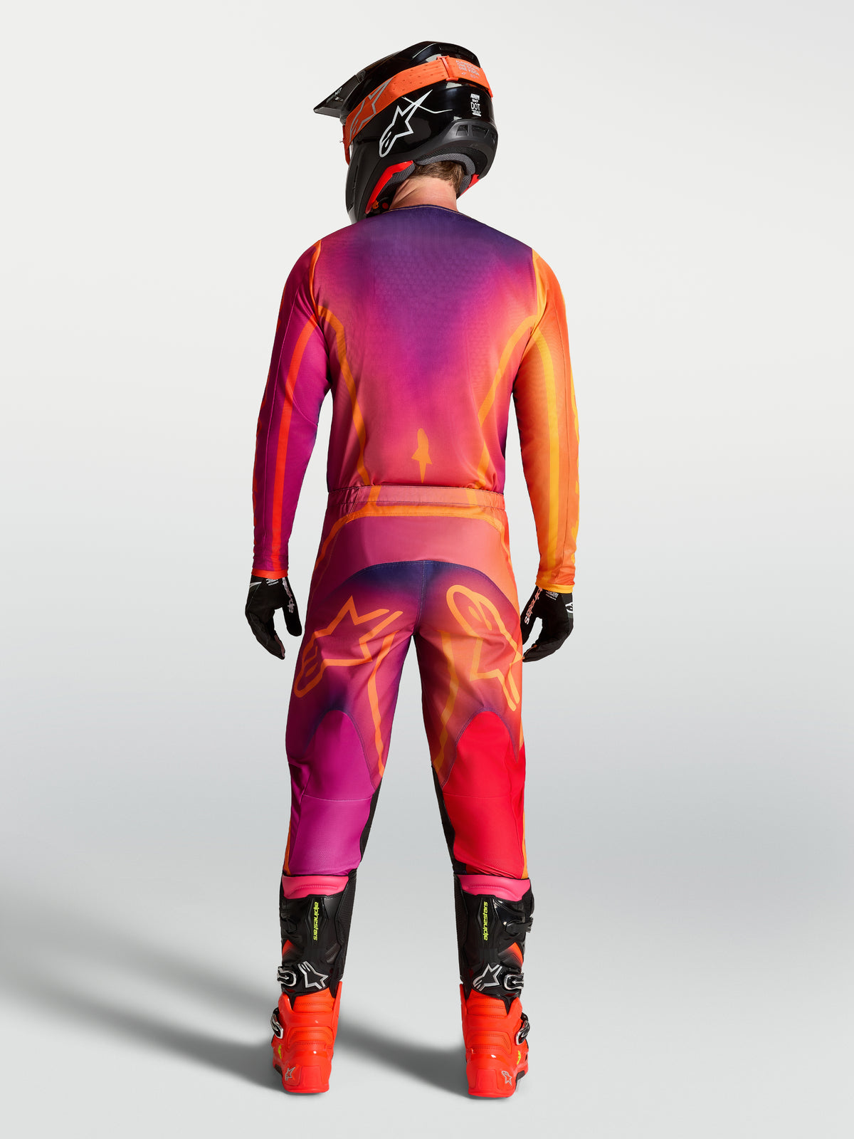 Alpinestars Fluid Kepler Jersey, men's purple and orange motocross gear on a rider with matching MX pants, seen from behind.