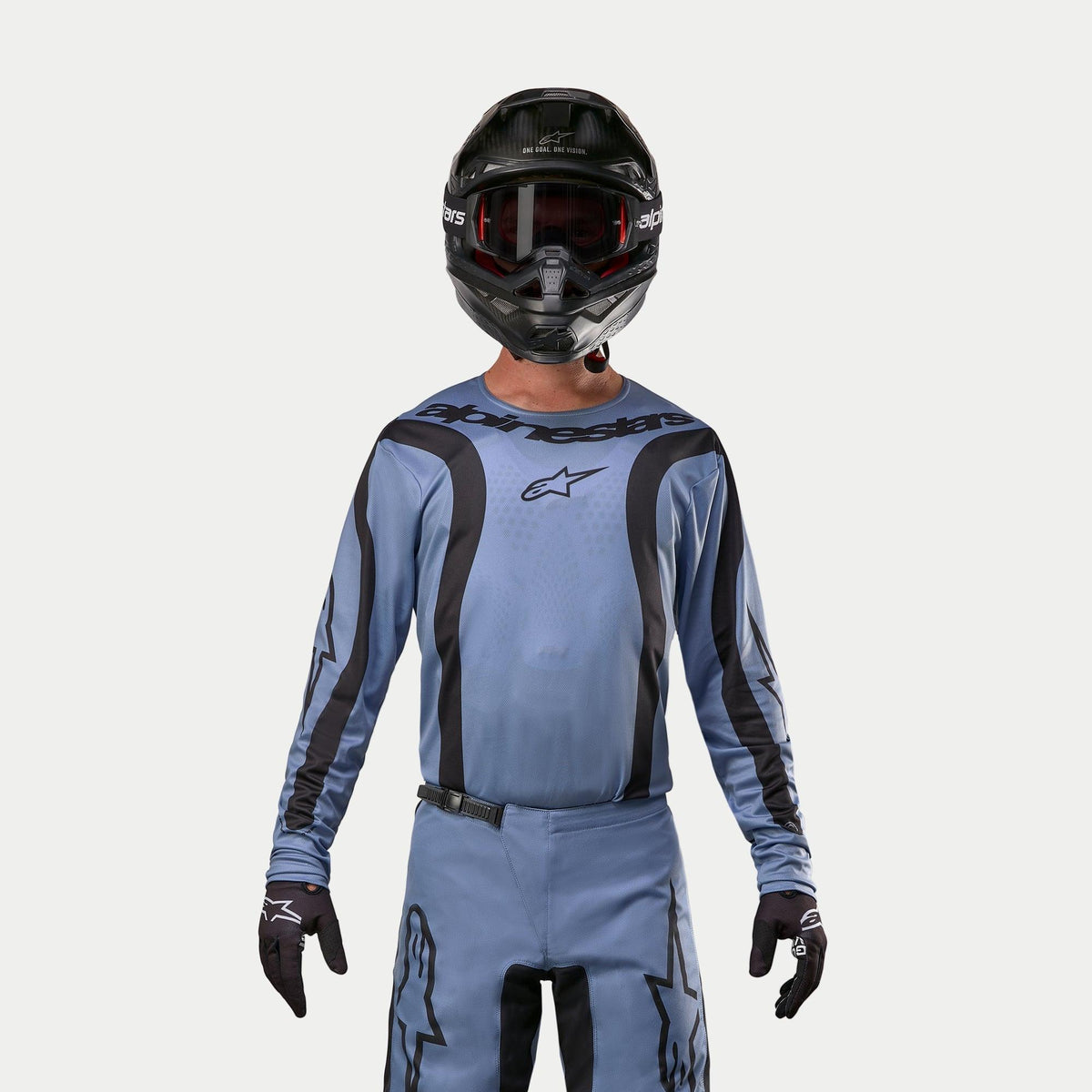 Alpinestars 2024 Fluid Lurv tröja, motocrosströja, ljusblå och svart, bärs av en förare med matchande byxor, svart hjälm med röda goggles och svarta handskar, koordinerad outfit för terrängkörning