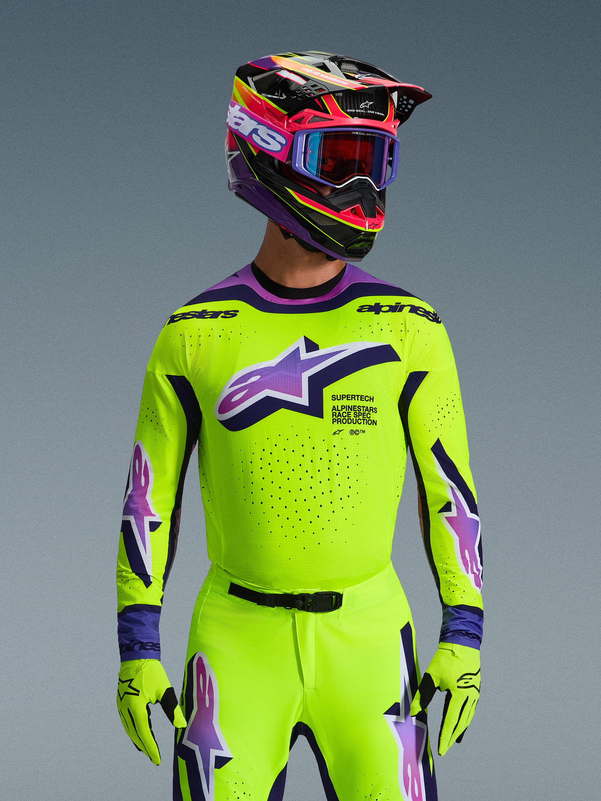 Alpinestars 2026 Supertech Vista-utrustningsset, motocrossförare i neongul tröja och byxor med lila och blå detaljer, stor Alpinestars-logotyp på bröstet, matchande färgglad hjälm och goggles, racingoutfit på proffsnivå