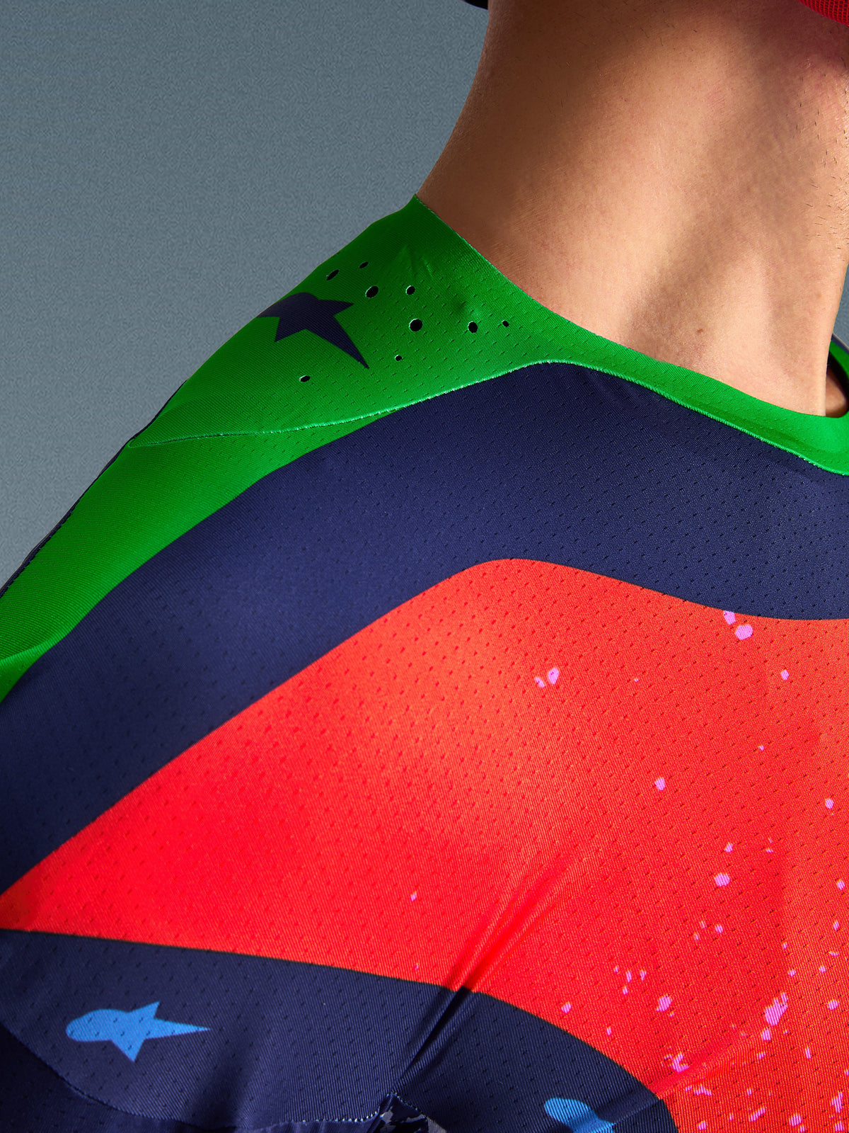 Närbild av Alpinestars Limited Edition Supertech Records Jersey, flerfärgad design med grön axel, marinblå och röda paneler, med laserskurna perforeringar och ventilerande meshtyg för professionell motocross-prestanda.