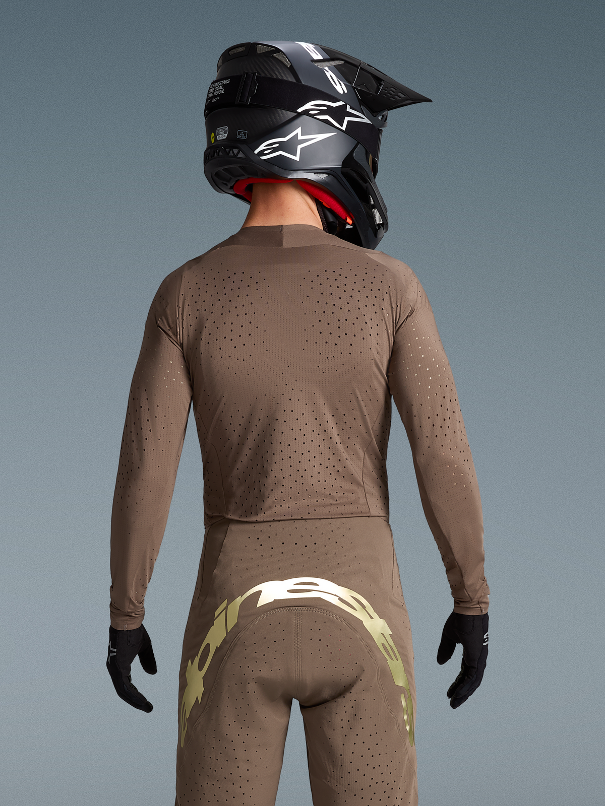 Alpinestars Begränsad Upplaga Supertech Air Set Gold, motocrossutrustning, brun och guld, vy bakifrån med laserutskuren ventilation.