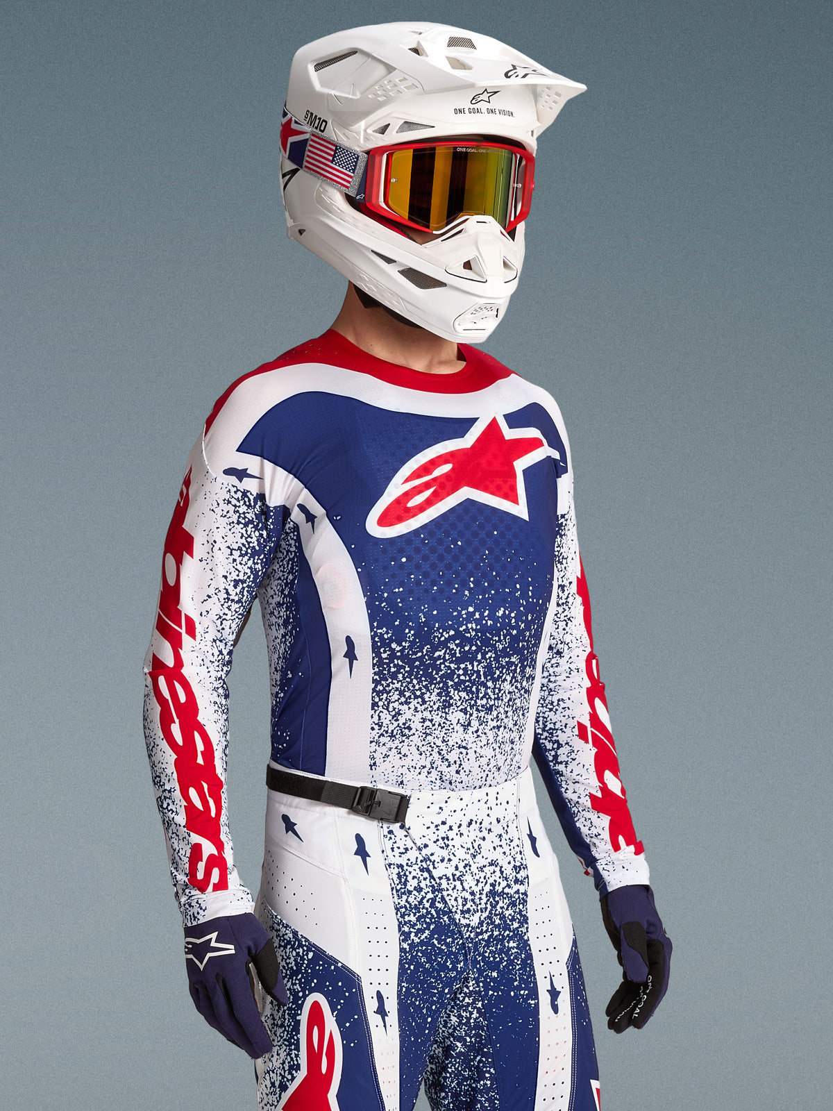 Alpinestars Techstar Unity tröja, röd och blå splatterdesign, motocrosströja för herrar på modell med matchande hjälm.