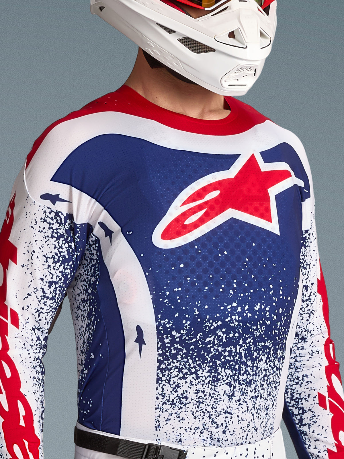 Alpinestars limited edition Techstar Unity tröja, röd, vit och blå motocrosströja, ventilerad racingpassform, med vit hjälm.