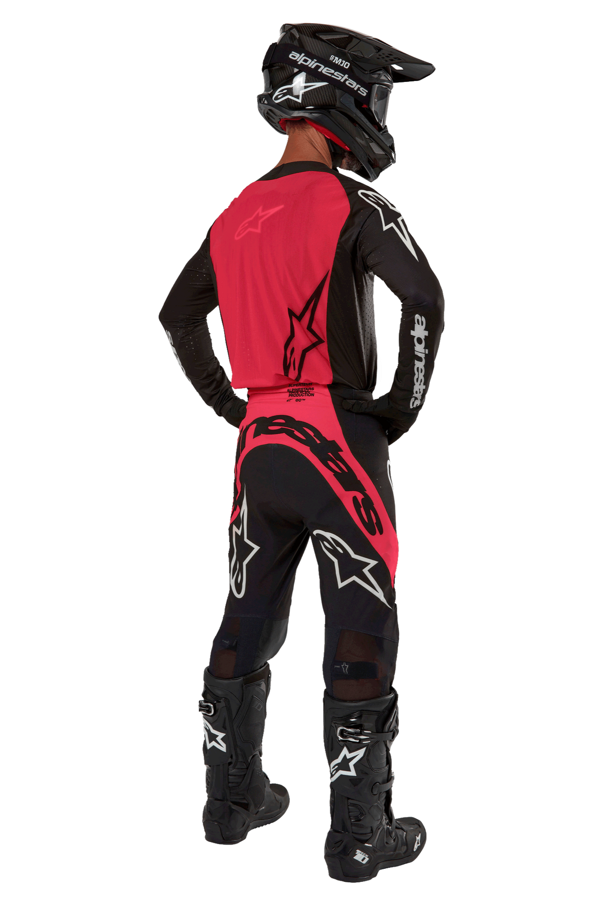 Motocrossförare sedd bakifrån bärande 2024 Supertech Ward Jersey i Black Red Berry, med en röd ryggpanel och svarta ärmar med vit Alpinestars-logotyp. Matchad med matchande motocrossbyxor, svarta Tech 10-stövlar och en svart kolfiberhjälm för en koordinerad professionell racingutrustning.
