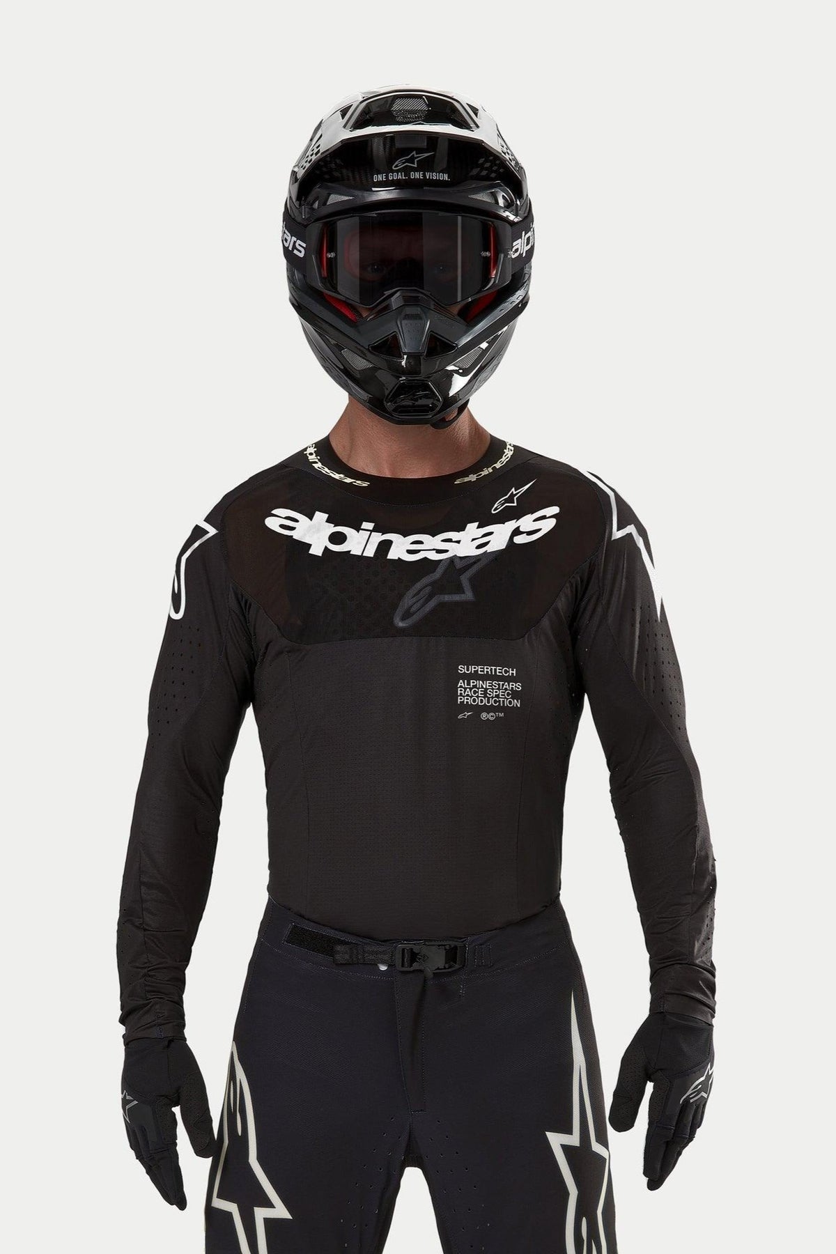 Motocrossförare klädd i Alpinestars 2024 Supertech Ward-tröja i svart, atletisk tävlingspassform med vit Alpinestars-logotyp på bröstet, laserskurna perforeringar och 'Supertech Race Spec'-text, matchad med svart hjälm och goggles för terrängkörning.
