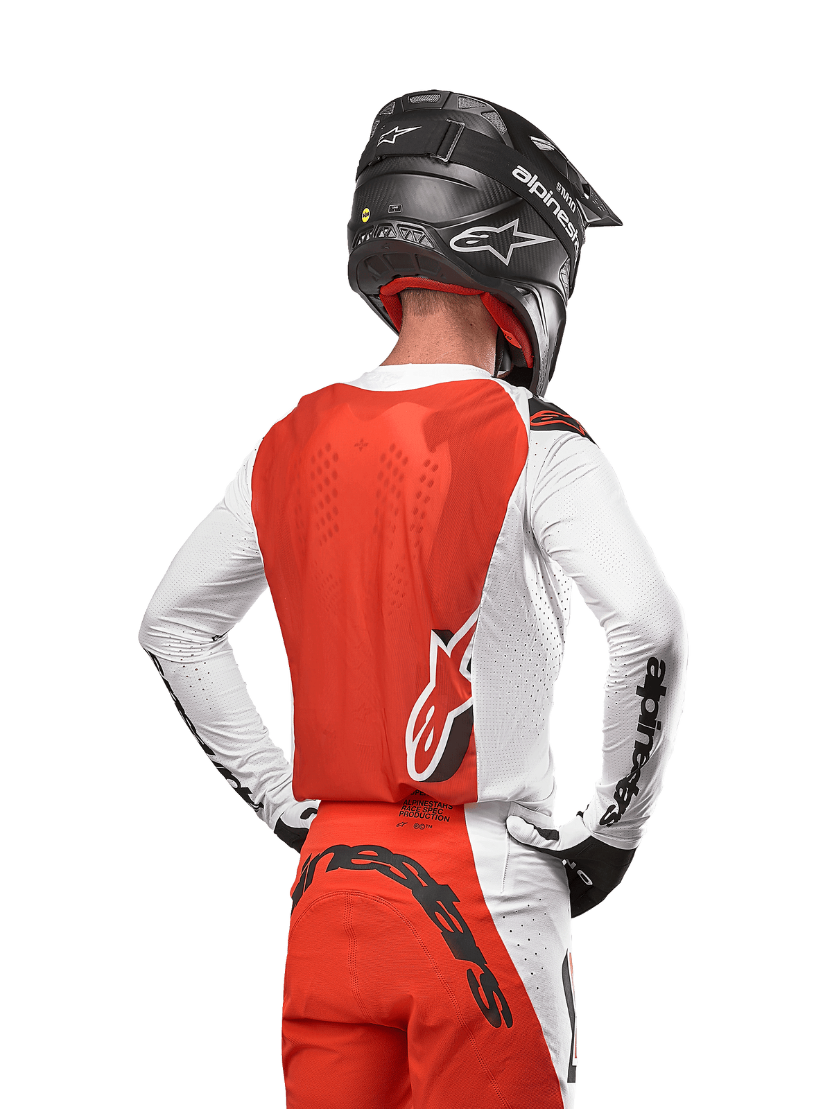 Motocrossförare i 2024 Supertech Ward Jersey i White Hot Orange, sedd bakifrån med orange ryggpanel och vita ärmar med svart Alpinestars-branding, matchad med matchande byxor och en svart hjälm, professionell utrustning för terrängkörning