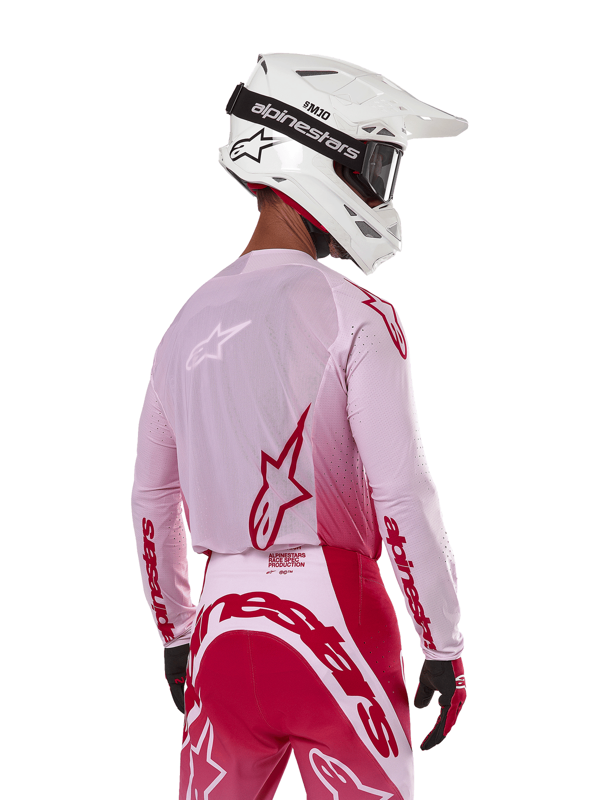 Motocrossförare sedd bakifrån iförd Alpinestars 2024 Supertech Dade Jersey i Red Berry Lilac, med ventilerande meshpaneler och röda Alpinestars-logotyper, matchad med röda och lila byxor och en vit Alpinestars-hjälm med goggles, professionell terrängutrustning