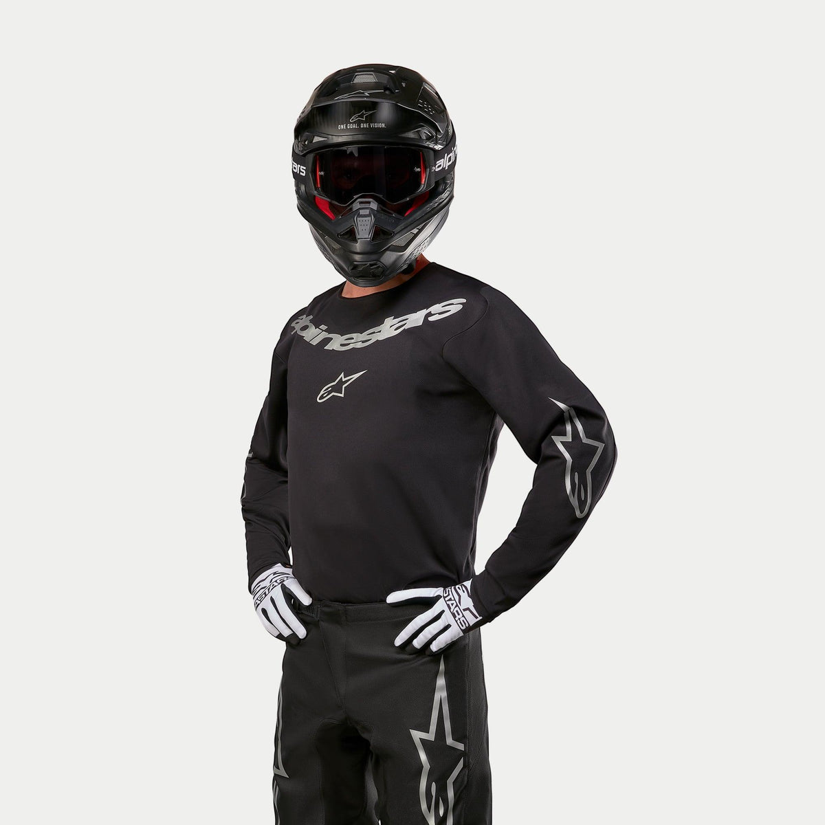 Motocrossförare i Alpinestars 2024 Fluid Graphite-tröja, svart och silver, matchad med svarta motocrossbyxor, svart hjälm med rödtonade goggles, vita och svarta handskar, silverfärgade logotyper på bröst och ärmar