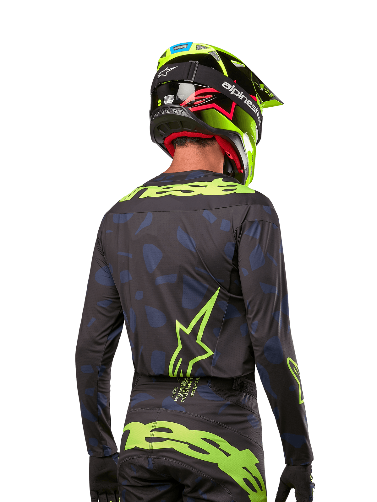 Vy bakifrån av en motocrossförare i Alpinestars 2024 Techstar Rantera Jersey i Black Navy Yellow Fluo, med framträdande neongul branding och logotyper på ryggen, matchad med matchande motocrossbyxor och en neongul hjälm för en komplett offroad-look.