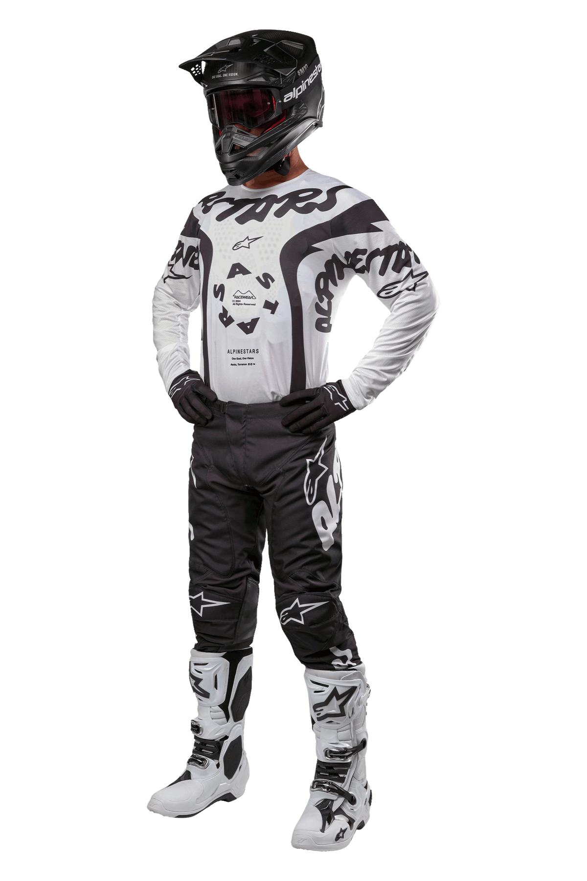 Motocrossförare i full utrustning med Alpinestars 2024 Racer Hana Jersey i vitt och svart, svarta motocrossbyxor med vita logotyper, svart hjälm, vita och svarta racingstövlar samt svarta handskar, professionell outfit för terrängkörning