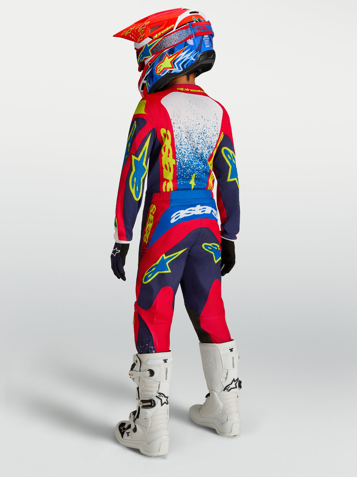 Alpinestars 2027 Ungdom Fluid Drag utrustningsset, blå och röd motocrossutrustning, vy bakifrån med vita motorcykelstövlar
