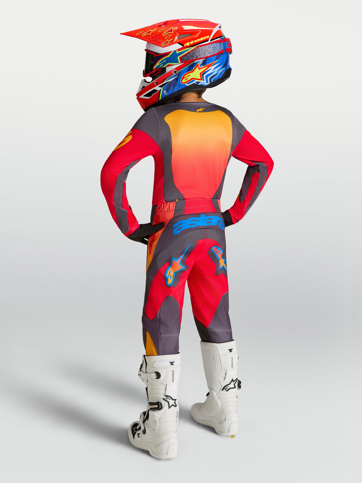 Alpinestars Ungdom Fluid Hunt gear set 2027, röd och grå motocrossutrustning i polytyg med vita stövlar, sett bakifrån.