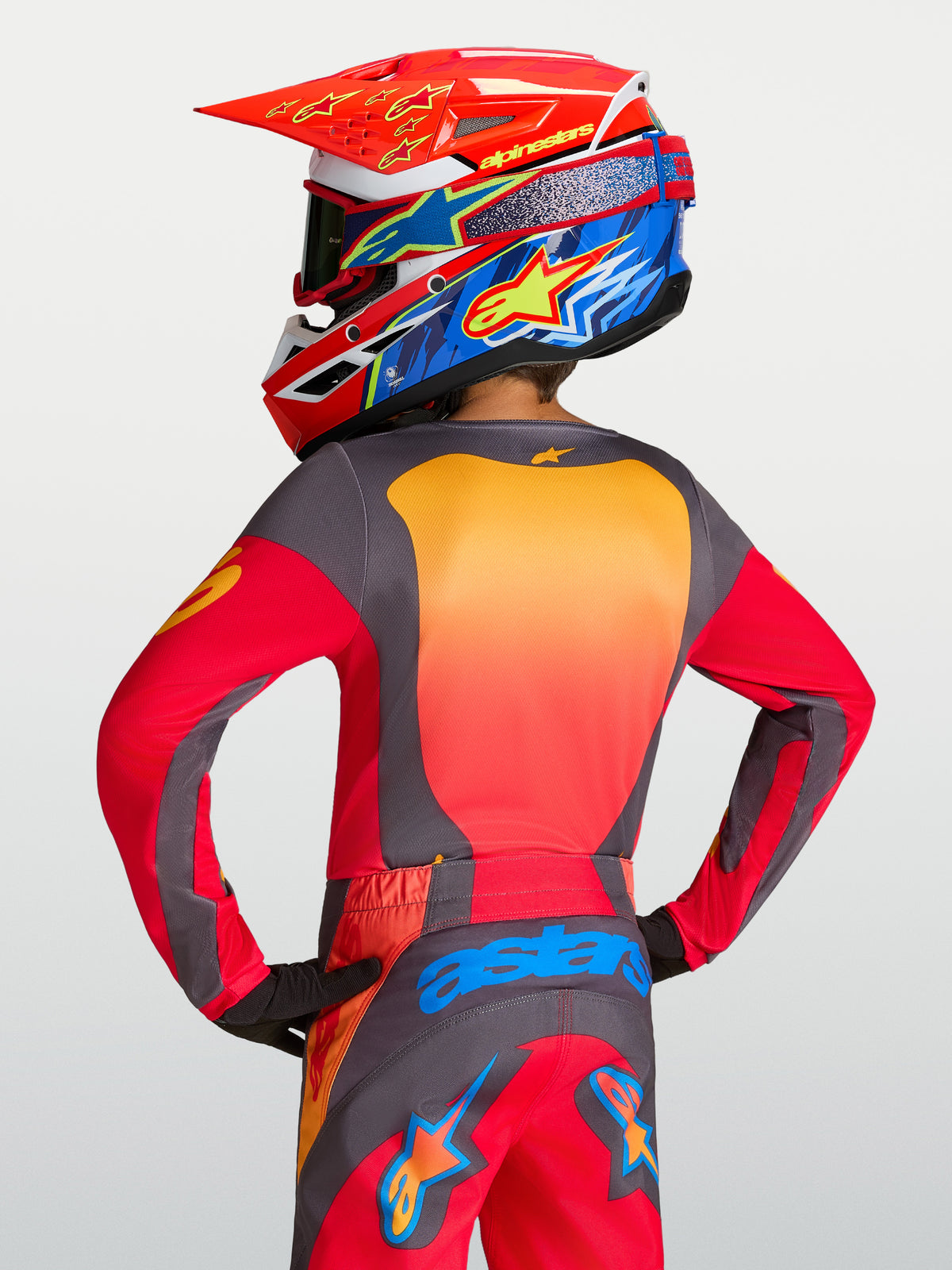 Alpinestars 2027 Fluid Hunt ungdomströja, röd och grå motocrosströja bärs av modell bakifrån med matchande utrustning.