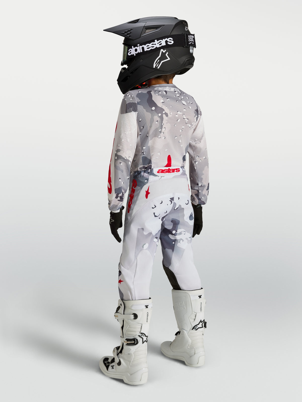 Alpinestars 2027 ungdom Fluid Lone Gear Set, grått och vitt kamouflagemönster, röda detaljer, vy bakifrån på modell.
