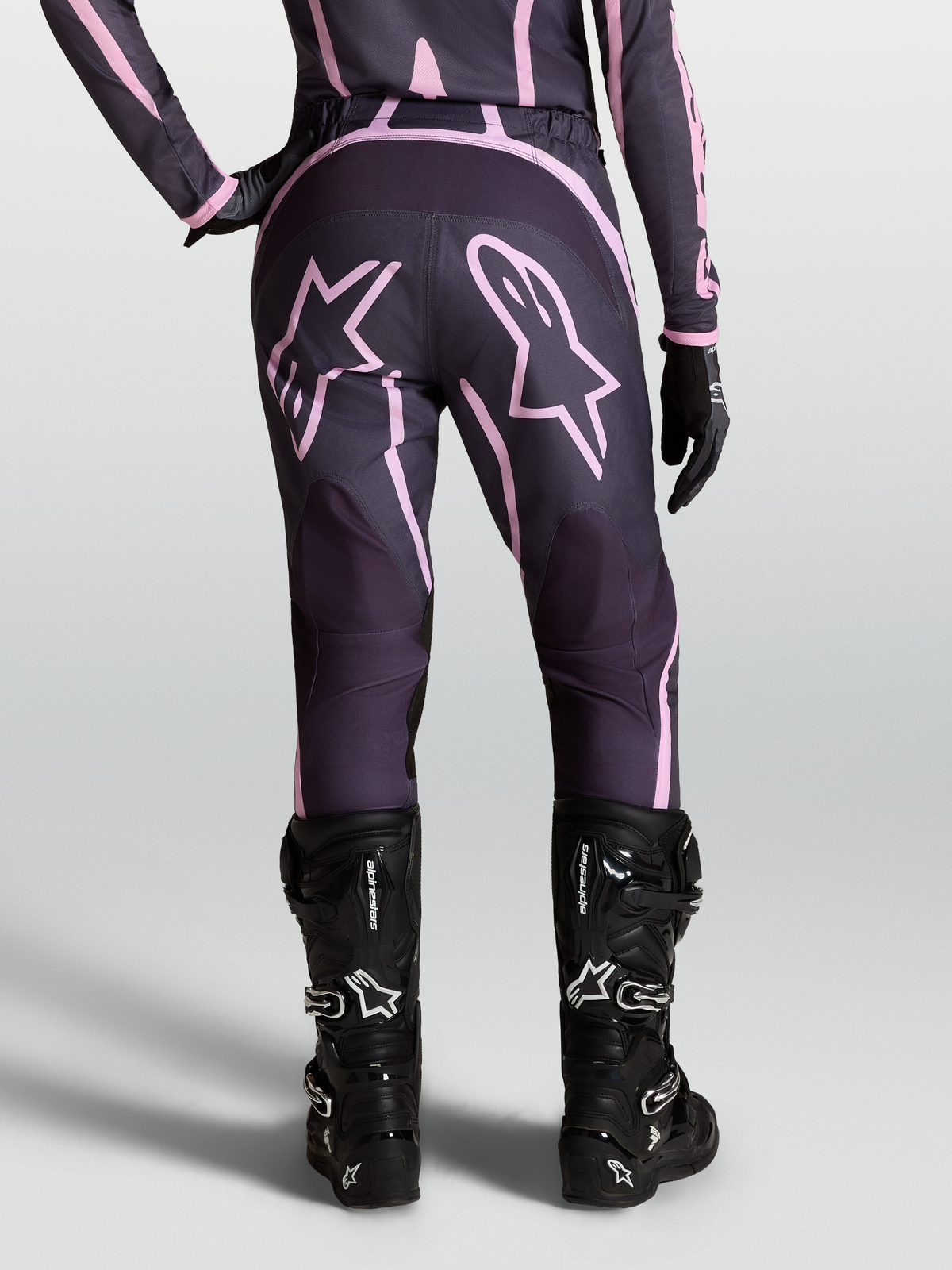 Alpinestars Stella Fluid Apex V2 dambyxor, motocrossbyxor i grått och rosa med stjärngrafik, svarta stövlar, terrängkörning