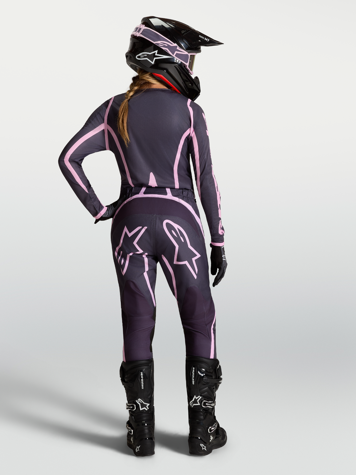 Alpinestars Stella Fluid Apex V2 motocrossbyxor för dam, grå och rosa, vy bakifrån på förare med matchande utrustning