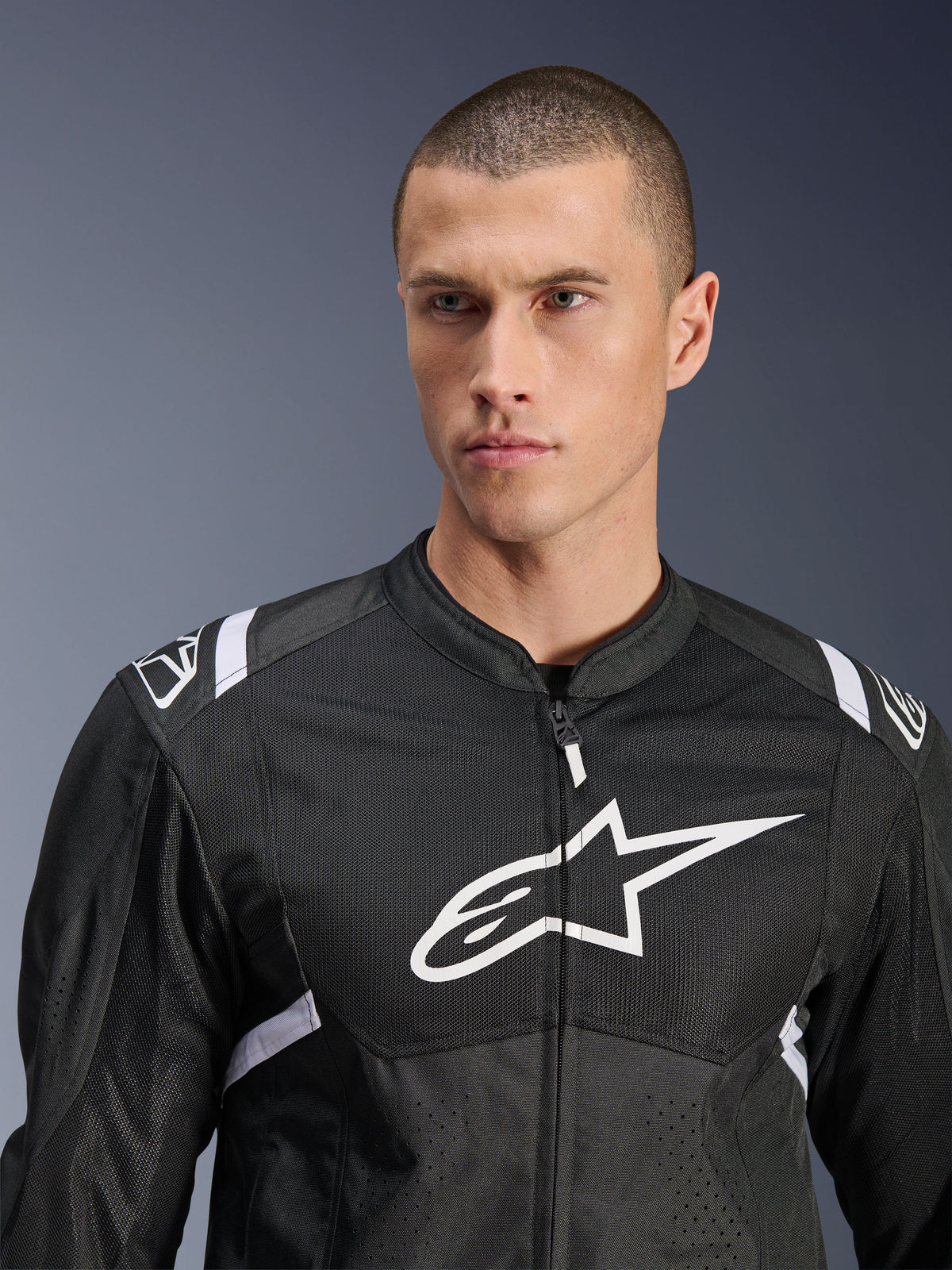Alpinestars T-SPS Air V2-jacka, motorcykeljacka i textil, svart och vit, med stor vit bröstlogotyp och meshpaneler, sportig passform bärs av manlig modell