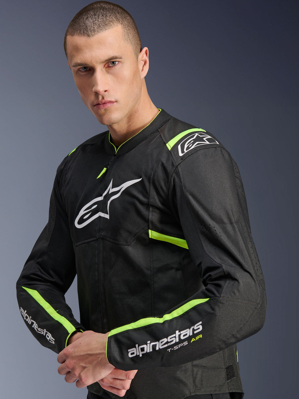 Alpinestars T-Sps Air V2-jacka, Black Yellow Fluo, textiljacka för motorcykel som bärs av en modell, med tech-meshpaneler för luftflöde, vit Alpinestars-logotyp på bröstet och gula fluo-detaljer på axlar och ärmar.