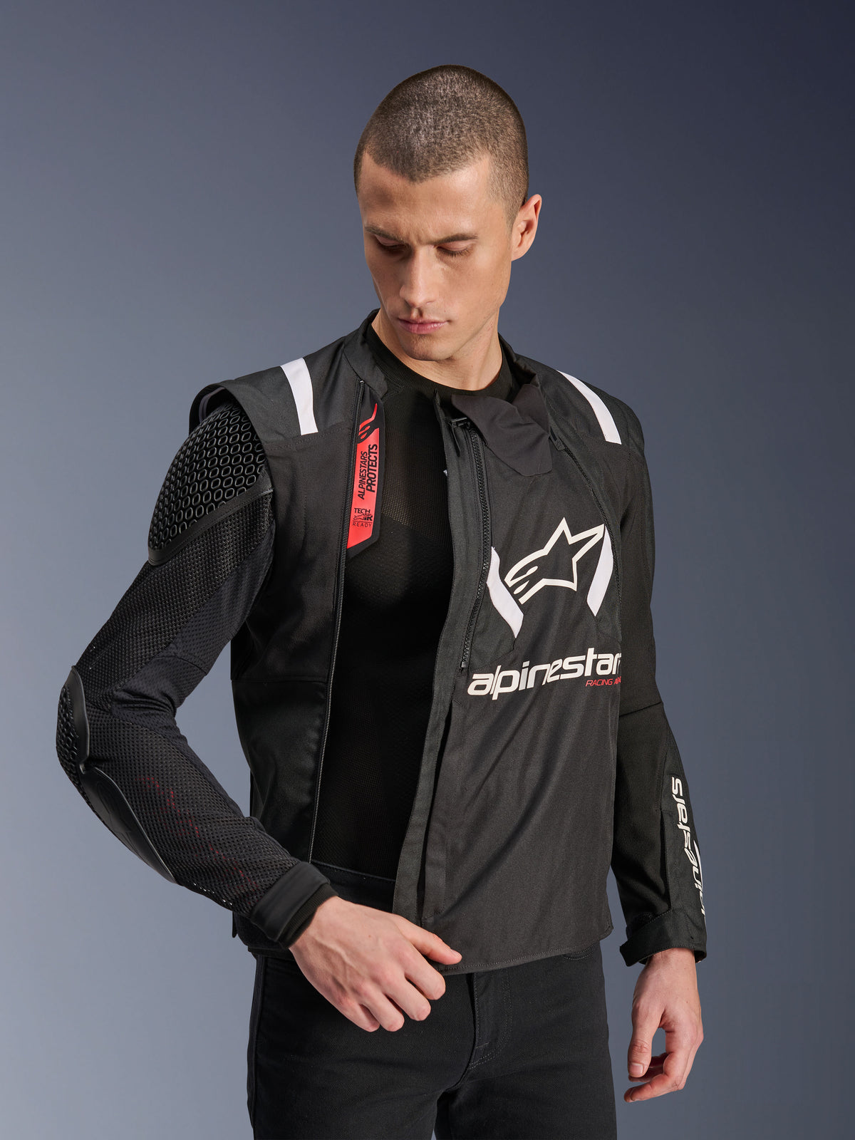 Alpinestars T-Stunt Air-jacka, svart och vit motorcykeljacka, bärs av manlig modell, visar modulär mesh-konstruktion och exponerat skydd på axel och armbåge, Alpinestars-logotyp på bröstet, Tech-Air® Ready-funktion, sportig skärning för vägkörning