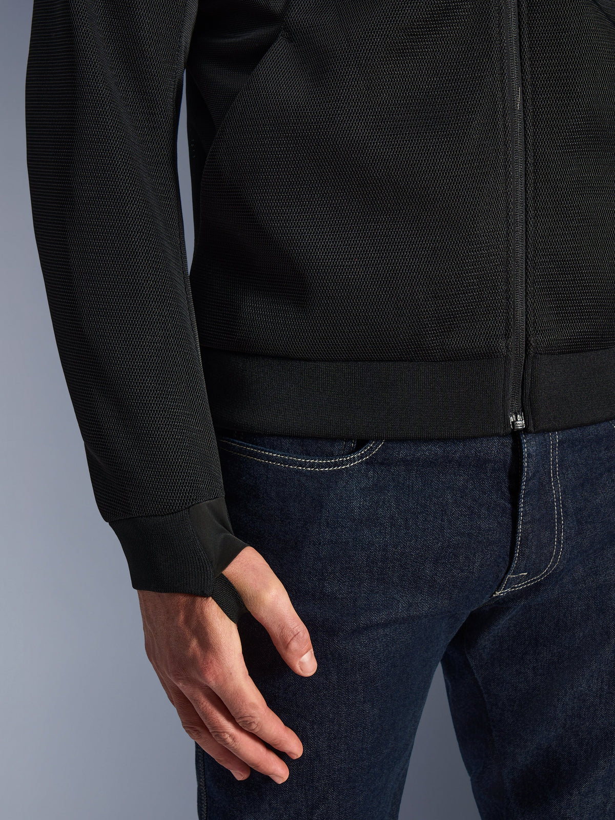 Alpinestars Chrome Superairflow Hoodie, svart, närbild på högresistent tekniskt 3D-mesh-tyg, med mudd i ribbad stretchjersey och elastisk tumögla, bärs med blå jeans