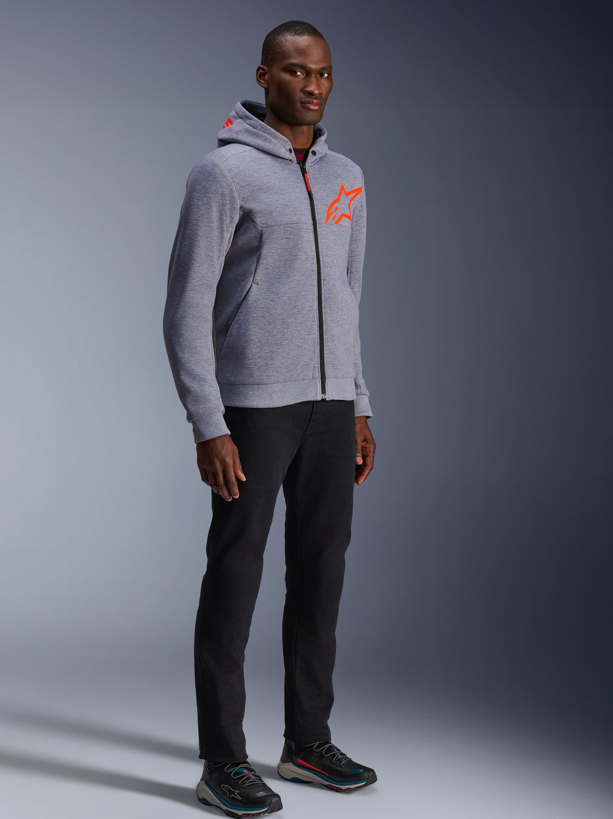 Alpinestars Chrome V2 Sport hoodie i grå och röd fluo, skyddande urban MC-jacka för herrar buren av en modell.