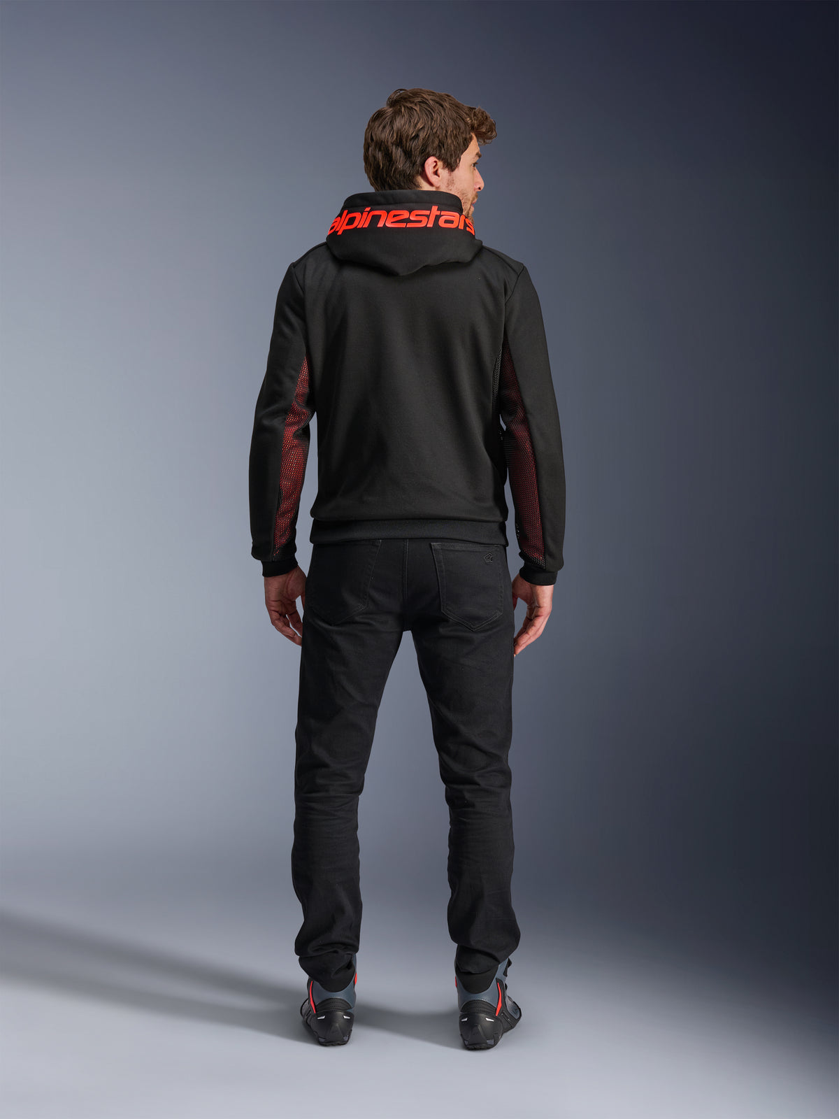 Alpinestars Chrome Air Sport Hoodie, Black and Red Fluo, back view of man wearing casual motorcycle jacket, featuring red Alpinestars branding on the hood and red mesh panels on the sleeves, paired with black pants.