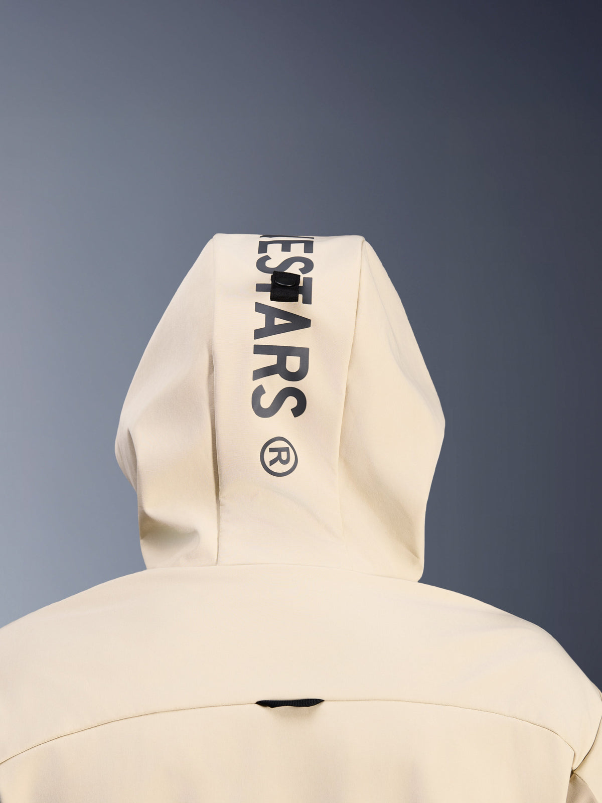 Alpinestars Radium Tech Hoodie i Mastic Aluminum, närbild bakifrån på huvan som visar vertikal svart Alpinestars-logotyp och huvans fästsystem, detalj av urban motorcykelutrustning