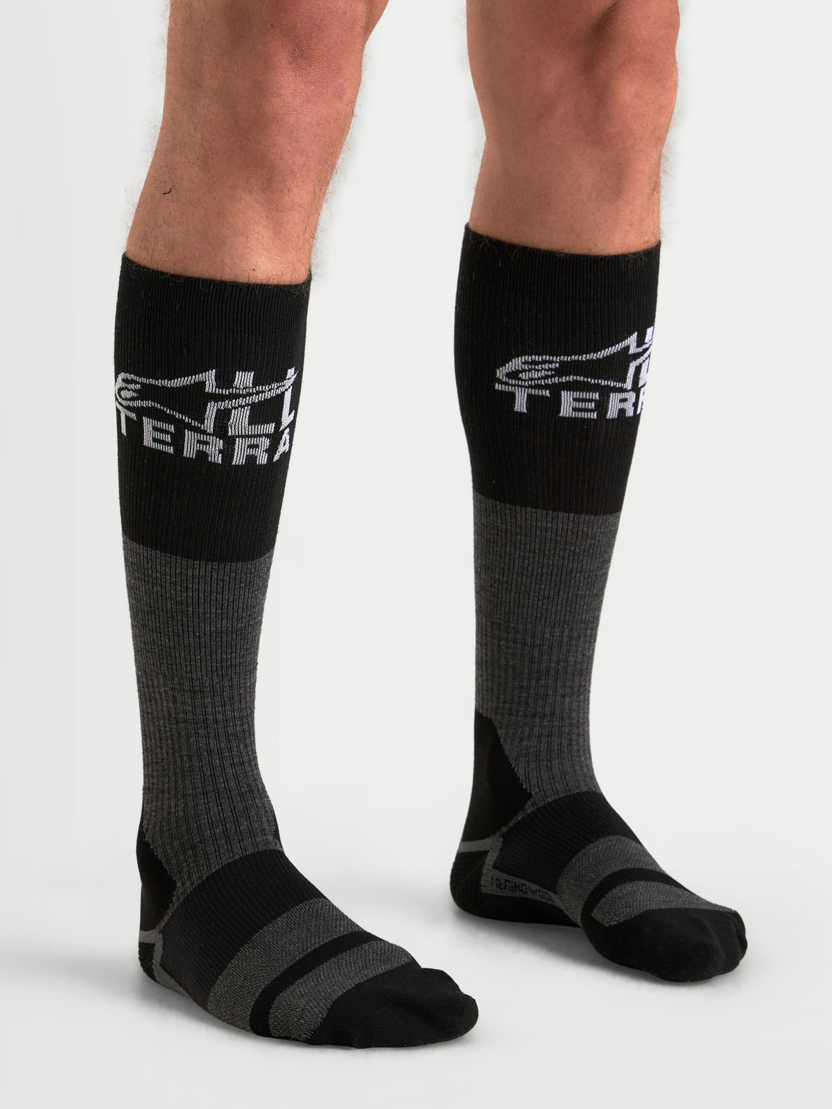 Alpinestars AT-8 Merino strumpor, äventyrsmotorcykelstrumpor, gråa och svarta, med värmande merinoullsblandning och All Terra-branding, bärs av en modell