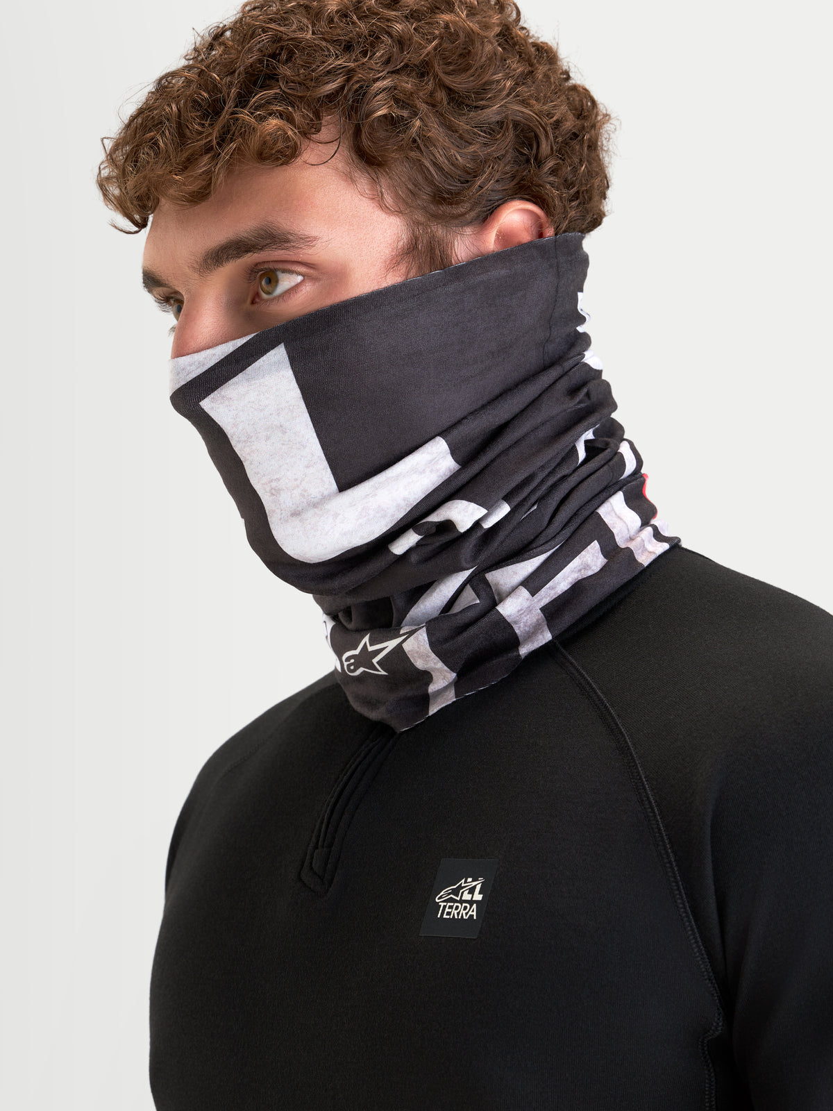 Alpinestars Buff All Terra Primaloft Neck Tube, cold-weather motorcycle neck warmer, black and gray, worn by a model showcasing lower face and neck coverage with insulated textile construction