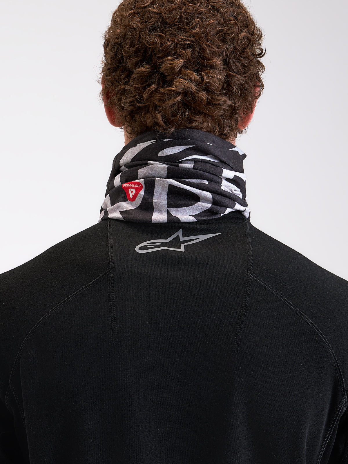 Alpinestars Buff All Terra Primaloft Neck Tube, cold-weather motorcycle neck warmer worn by a model, black and gray with PrimaLoft insulation logo and reflective Astar branding on the back