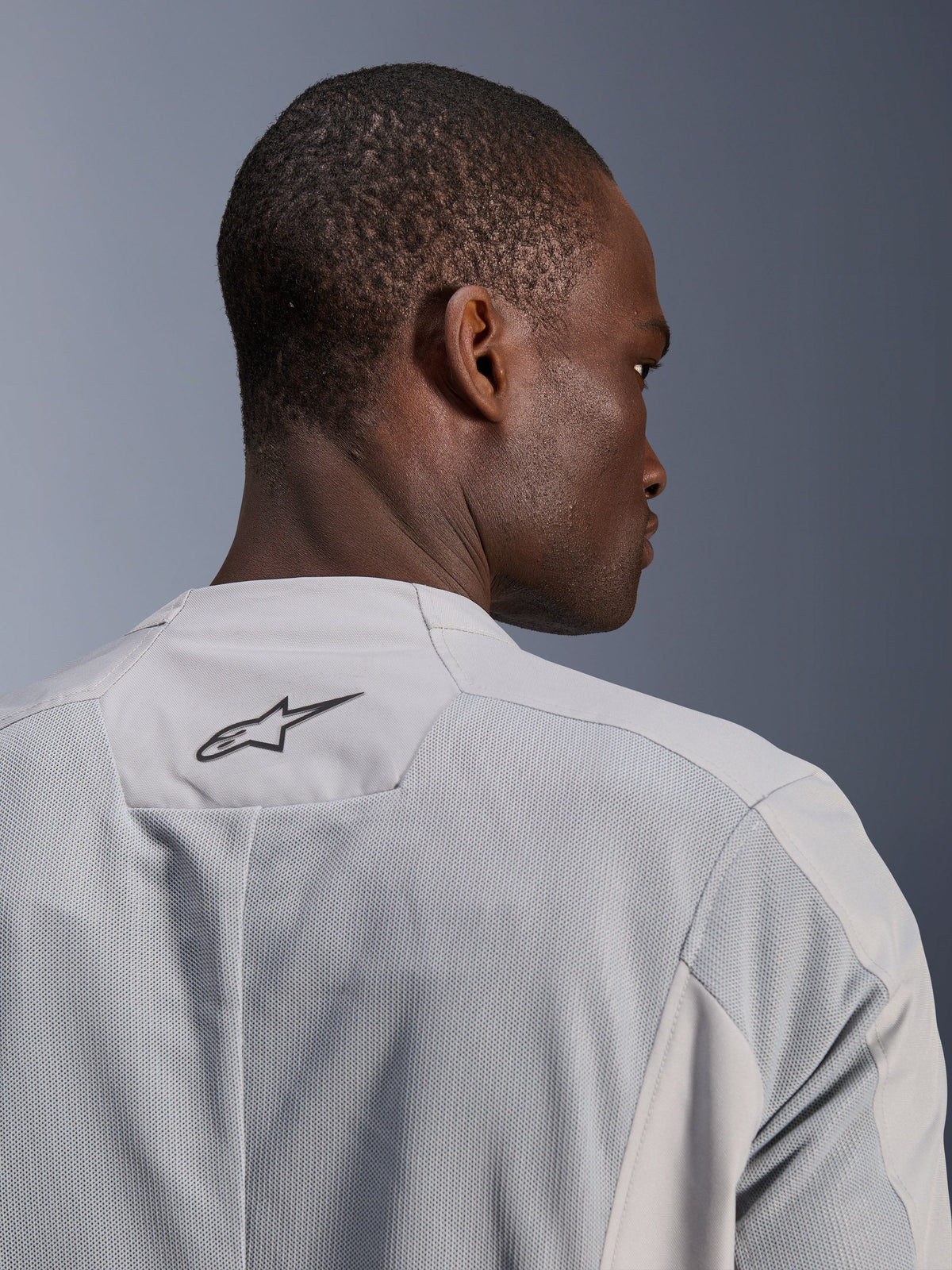 Alpinestars C-1 Air-jacka, silvergrå motorcykeljacka i textil, närbild bakifrån med tekniska meshpaneler för luftflöde och en svart Alpinestars-logotyp på den övre ryggen, urban förarestetik