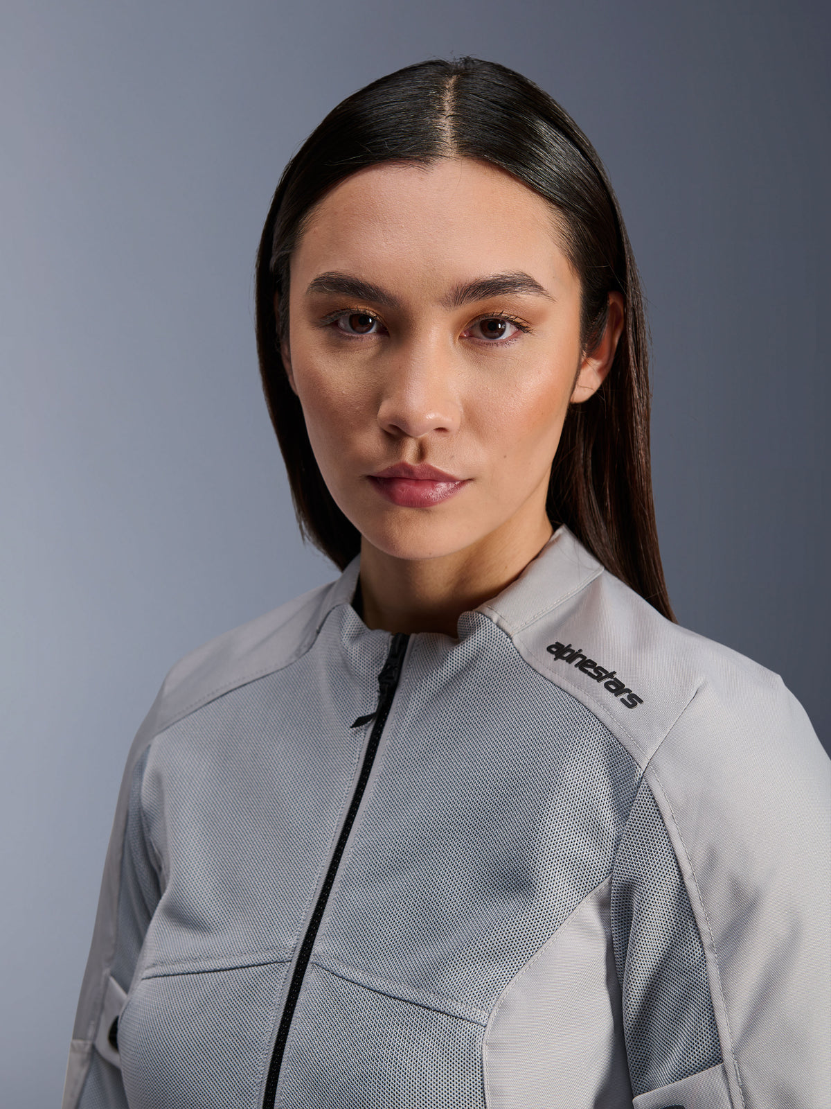 Alpinestars Stella C-1 Air Jacket, Women's Silver Motorcycle Jacket, close-up portrait showing tech mesh ventilation panels and black logo on shoulder, urban contemporary riding gear