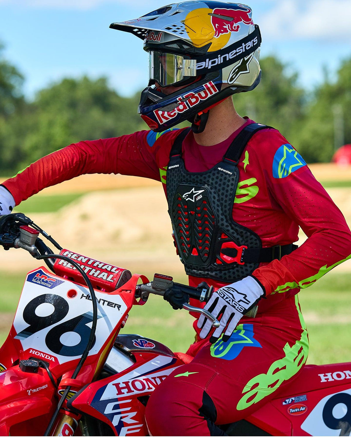 Motocrossförare som bär Alpinestars A-5 Plasma bröstskydd i svart och rött, tillsammans med en röd och limegrön racingtröja och byxor, sittande på en röd Honda-motorcykel, högpresterande skyddsutrustning för terrängkörning