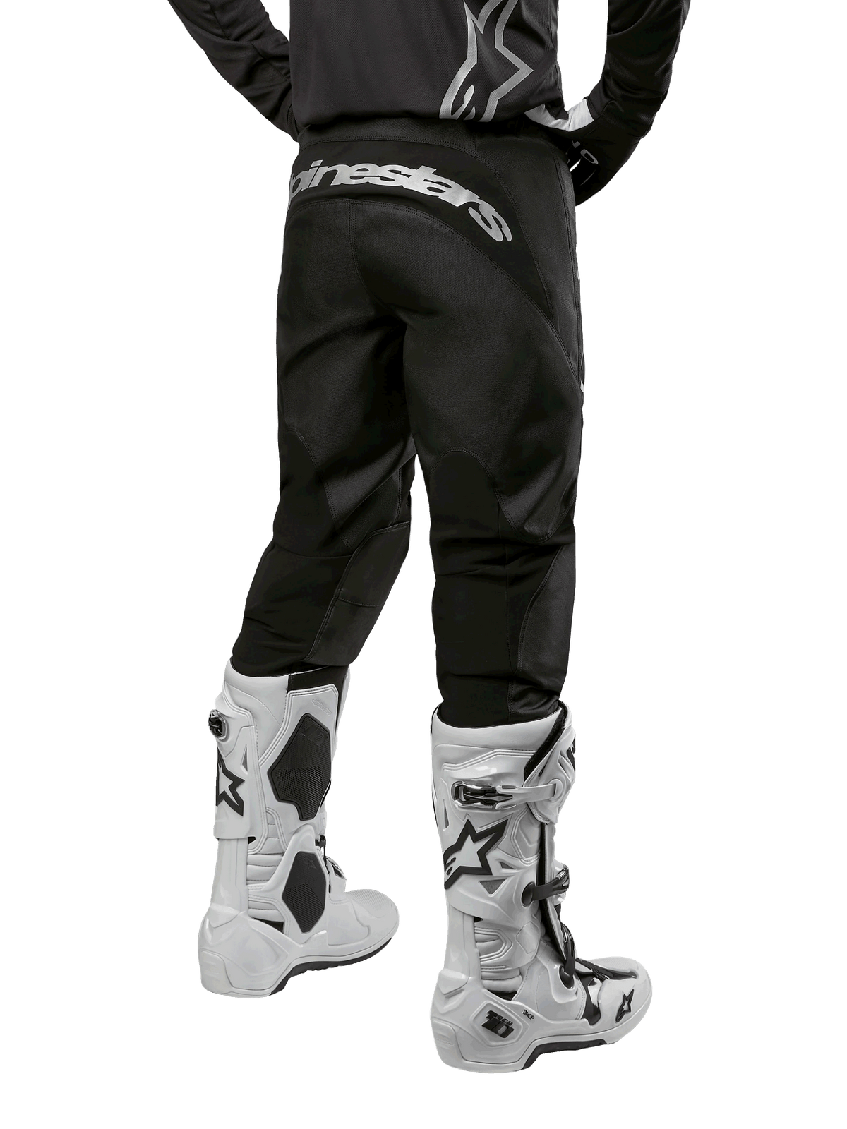 Alpinestars 2024 Fluid Graphite Pants, Motocross Pants, Black and Silver, rear view showing silver Alpinestars branding on the back yoke, worn with white and black motocross boots, durable textile design for off-road riding