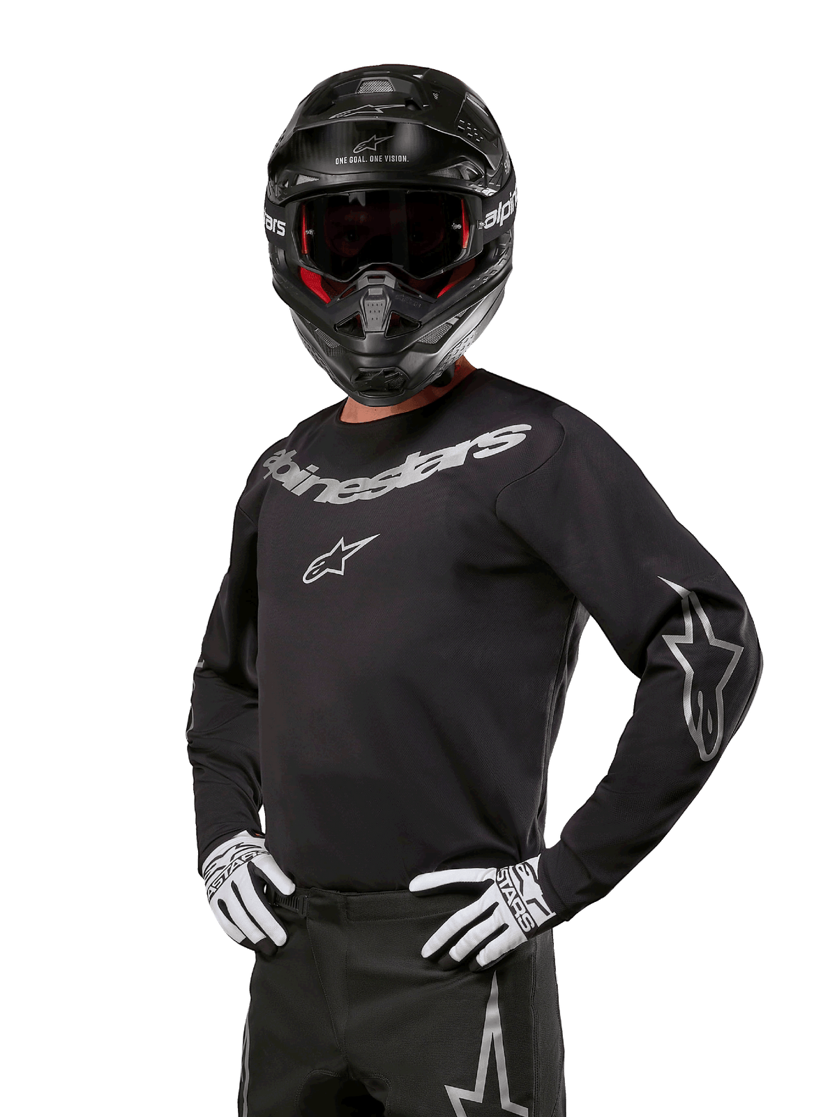 Alpinestars 2024 Fluid Graphite Jersey, motocrossjersey i svart och silver, långärmad atletisk passform, bärs med en svart hjälm och vita handskar, silverfärgade Alpinestars-logotyper, racingutrustning för terrängkörning