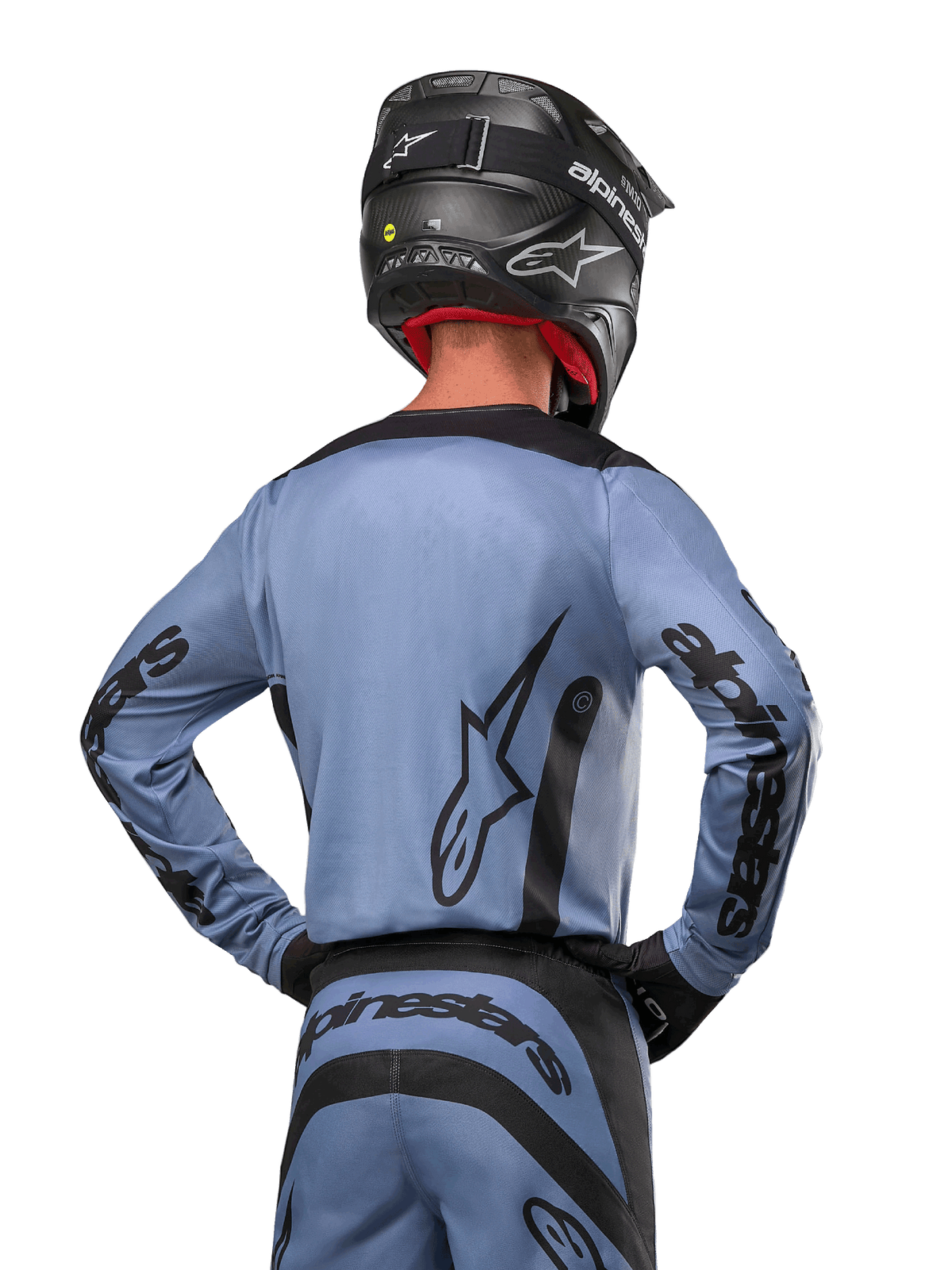 Alpinestars 2024 Fluid Lurv-tröja, motocrosströja, ljusblå och svart, vy bakifrån av förare som visar stor stjärnlogotyp och logotyp på ärmarna, bärs med en svart hjälm och matchande terrängbyxor, professionell racingutrustning