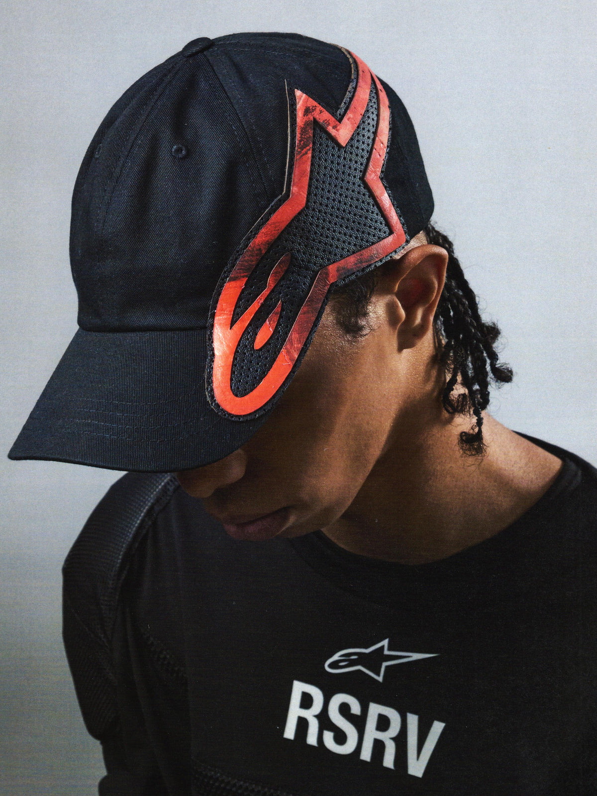 Alpinestars RSRV Lowside Hat, svart keps med röd och svart flamliknande design, unisex streetwear-kollektion, perforerad konstruktion