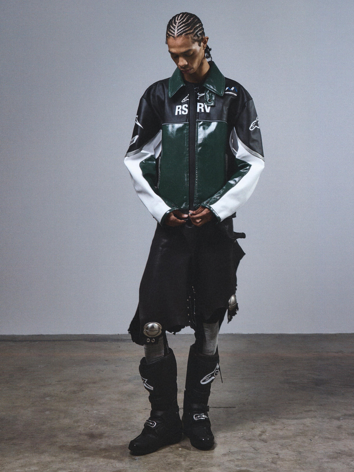 RSRV Alloy Leather Jacket, Premium Streetwear Motorcycle Jacket, Green Black and White, Glossy Leather Construction, RSRV Logo Branding, Worn with Black Boots and Metallic Accent Pants