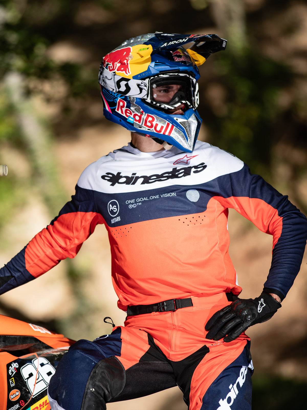 Motocrossförare i Alpinestars Pro-Dura-utrustning, marinblå, starkt orange och vit tröja med central Alpinestars-logotyp, matchande Pro-Dura-byxor, Red Bull-hjälm och svarta handskar, koordinerad outfit för professionell endurokörning