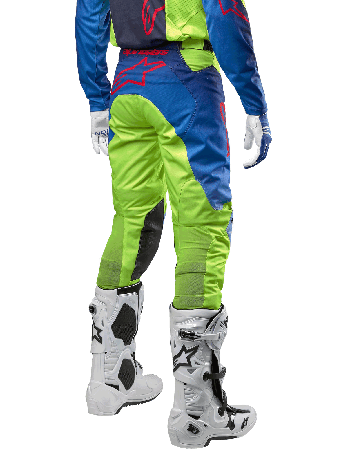 Alpinestars 2024 Racer Hoen byxor, motocrossbyxor, neongula och mörkblå (Blue Night Navy), sedda bakifrån, med en röd Alpinestars-logotyp, bärs med matchande tröja, vita handskar och vita motocross-stövlar, slitstarkt textilmaterial för terrängkörning