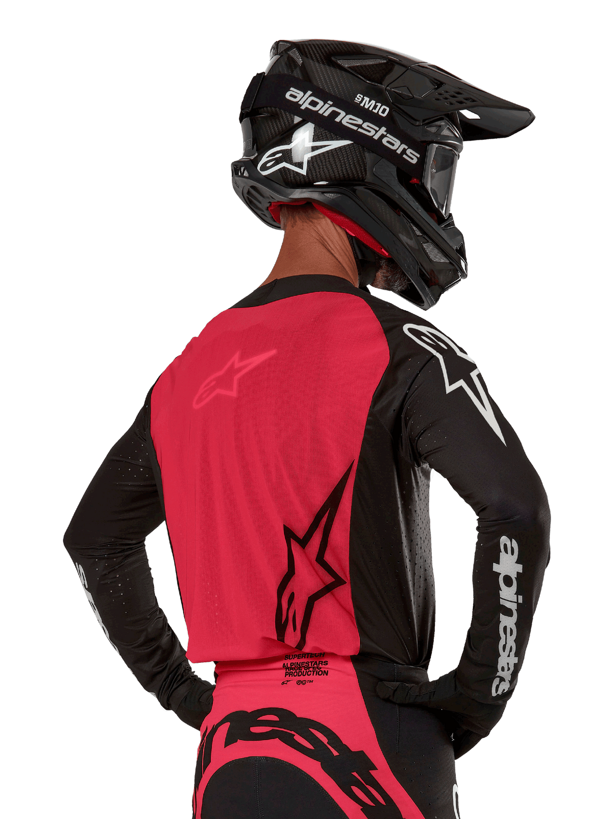 Alpinestars 2024 Supertech Ward tröja, motocrosströja, svart och bärröd, baksida som visar röd meshpanel och svarta ärmar med vit logotyp, bärs med en svart kolfiberhjälm och handskar, atletisk race-passform för terrängkörning