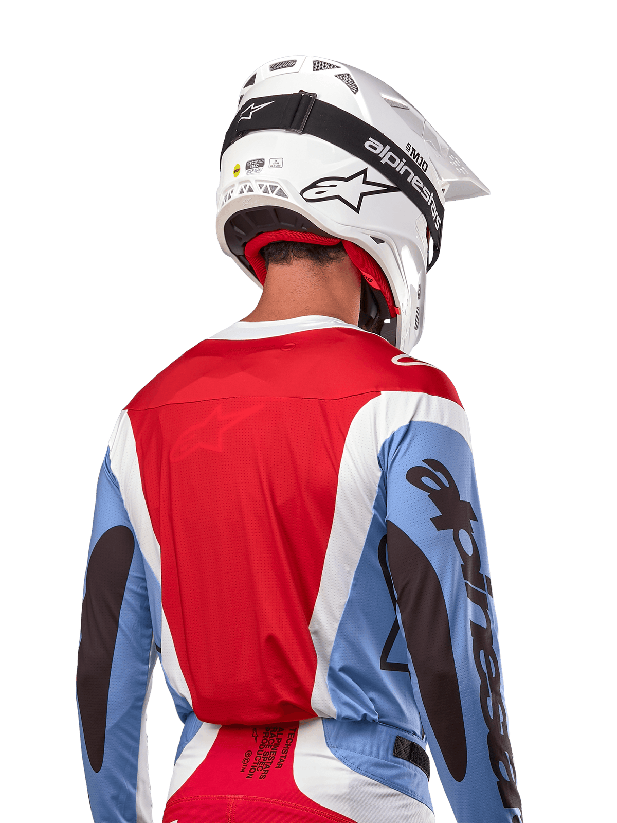 Alpinestars 2024 Techstar Ocuri-tröja, motocrosströja, ljusblå, marsröd och vit, vy bakifrån av förare med matchande vit hjälm och svarta goggles, tydlig svart logotyp på ärmarna, ergonomisk race-passform för terrängprestanda